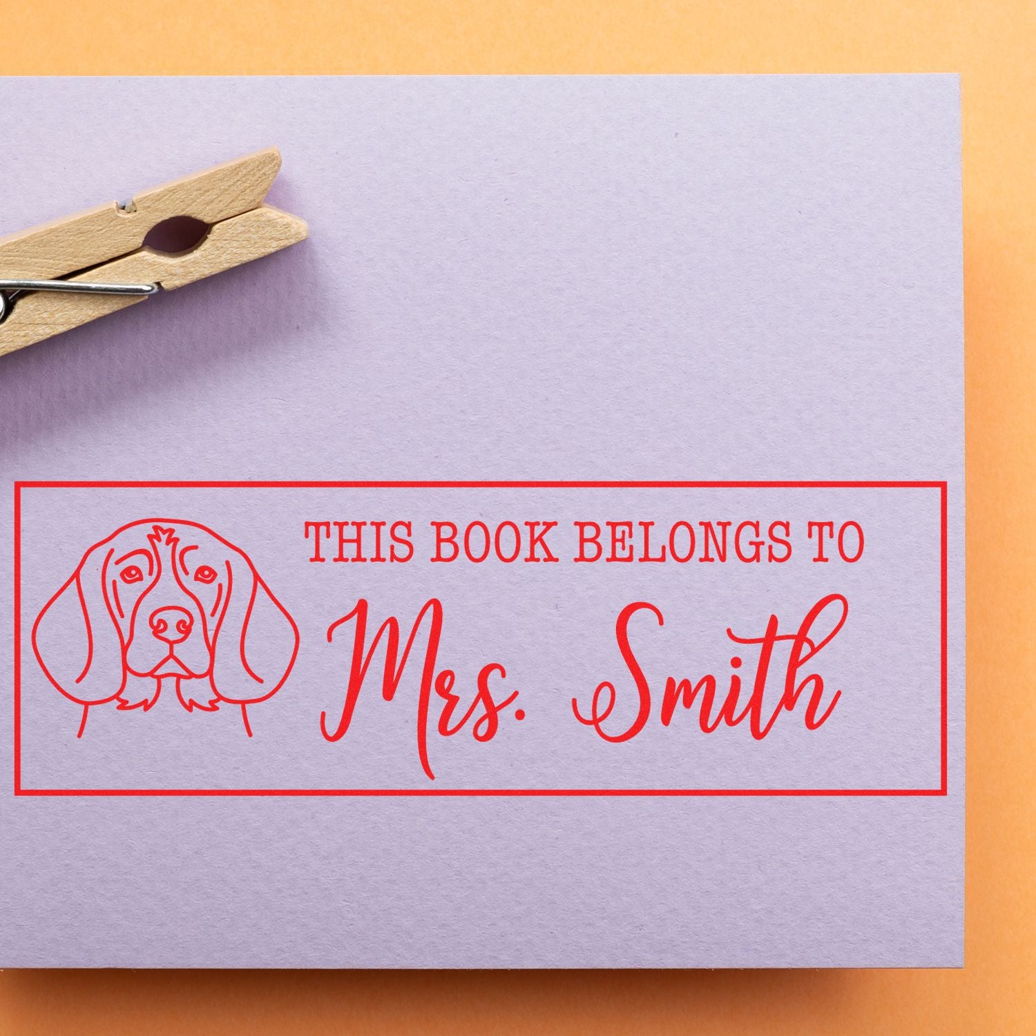 Personalized rubber book stamp with dog design and This Book Belongs to Mrs. Smith text for custom library labeling.