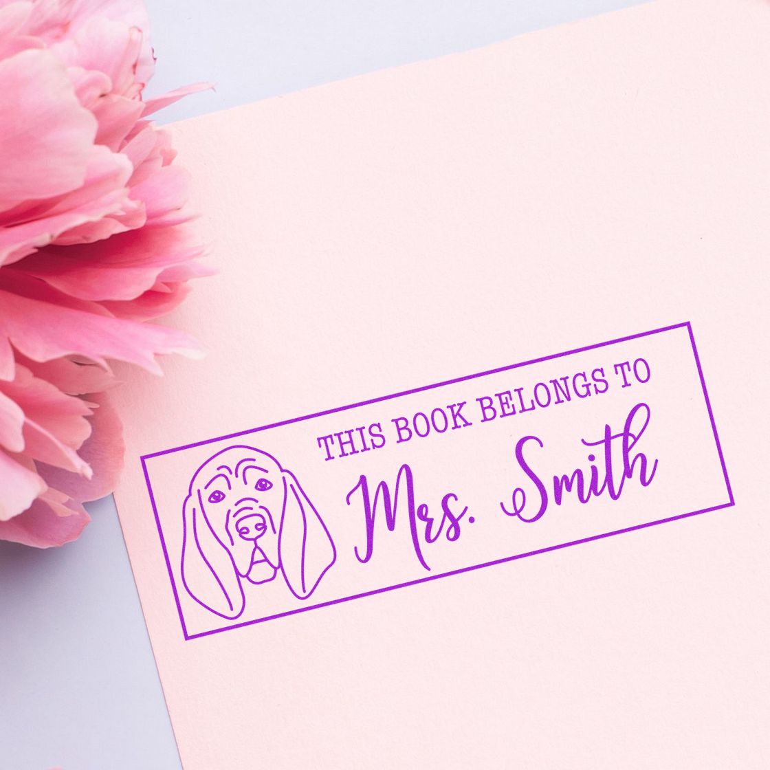 Personalized dog book stamp reading This Book Belongs to Mrs. Smith, a custom purple rubber stamp for books and libraries.