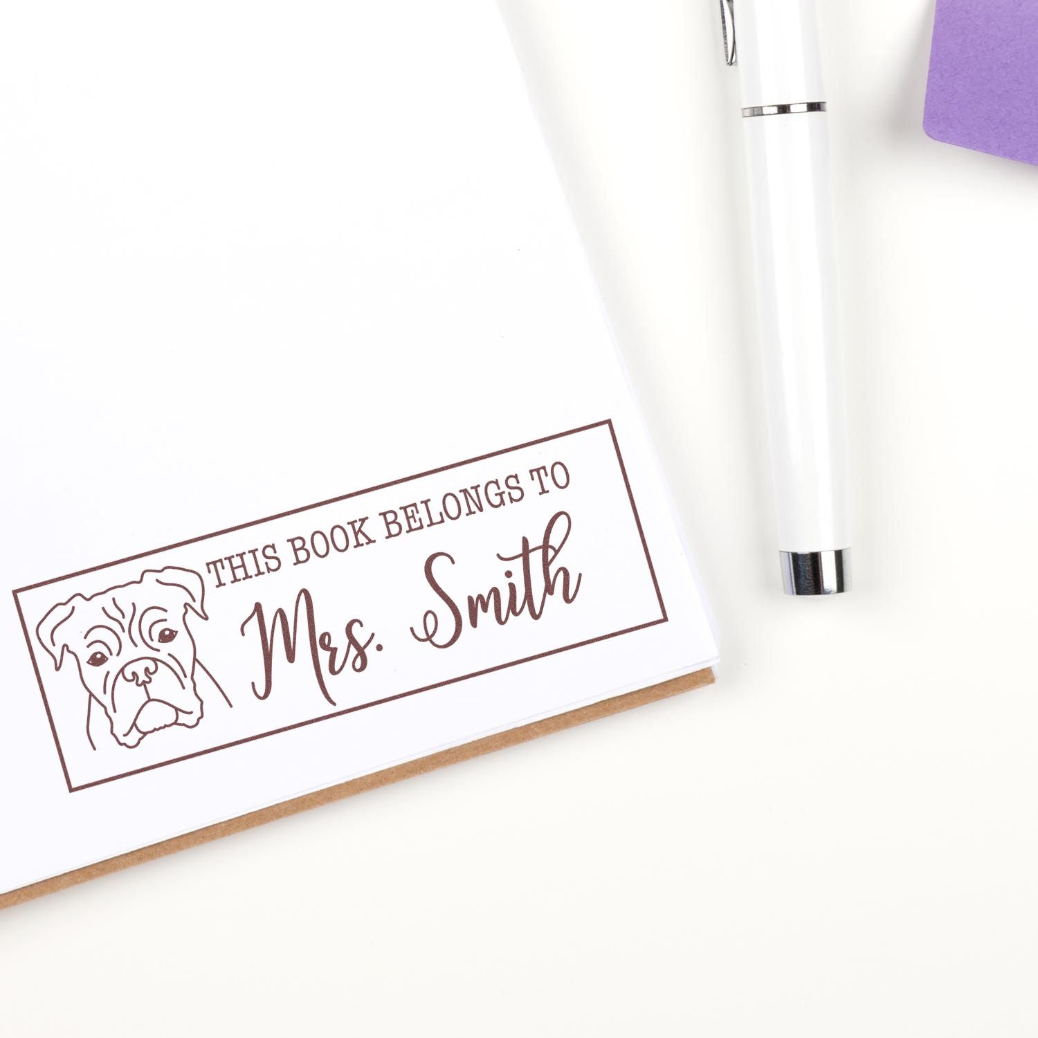 Custom rubber book stamp with dog illustration and This Book Belongs to Mrs. Smith text for personal library marking.
