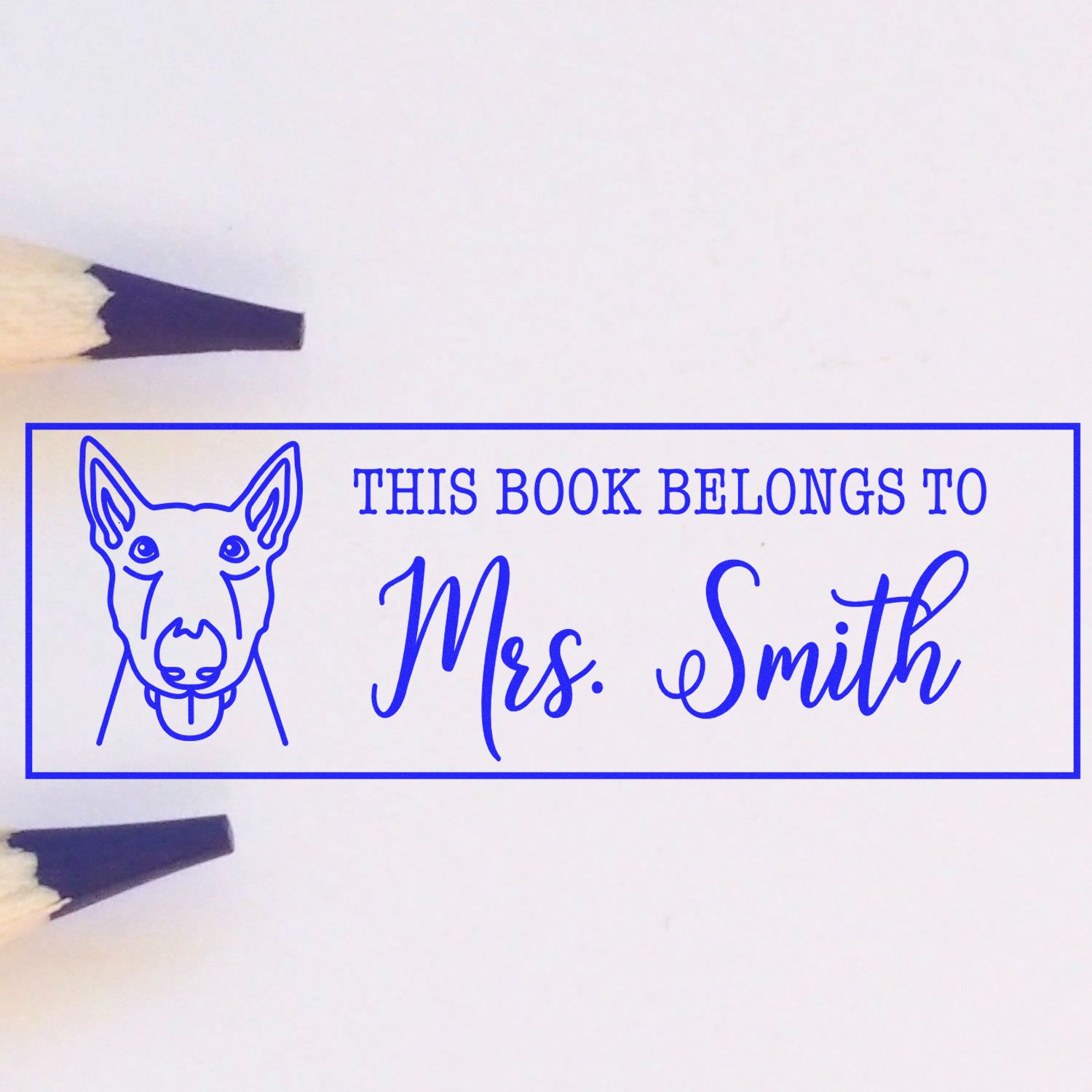 Custom rubber book stamp with dog illustration and This Book Belongs to Mrs. Smith for personalized library books.