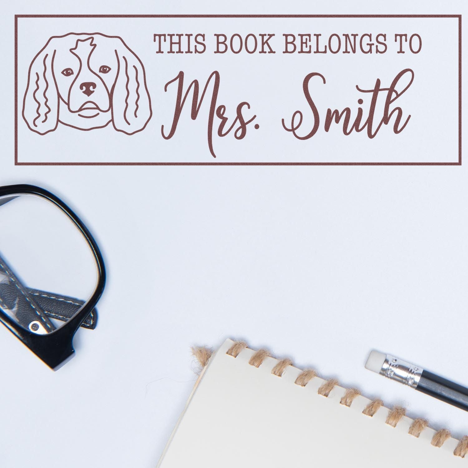 Personalized rubber book stamp with dog illustration and This Book Belongs to Mrs. Smith for custom library labeling.