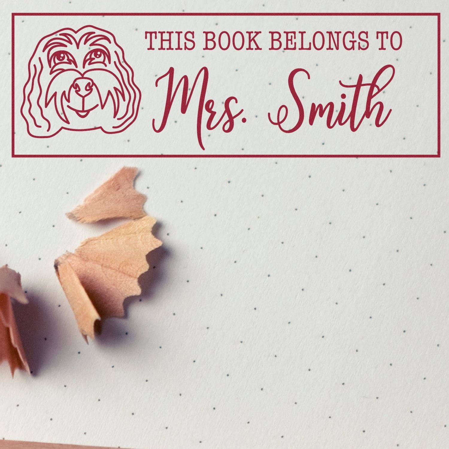 Personalized rubber book stamp with dog illustration and This Book Belongs to Mrs. Smith text for library books.