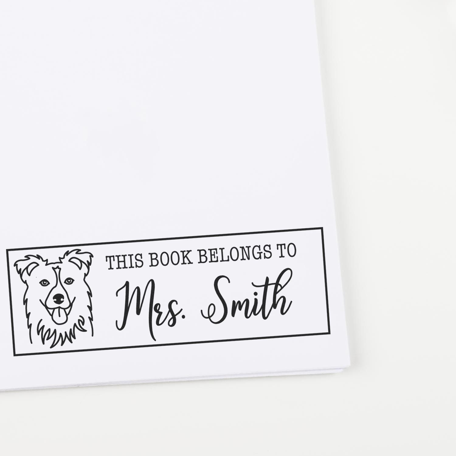 Custom rubber book stamp with dog design and personalized This Book Belongs to Mrs. Smith text for library books.