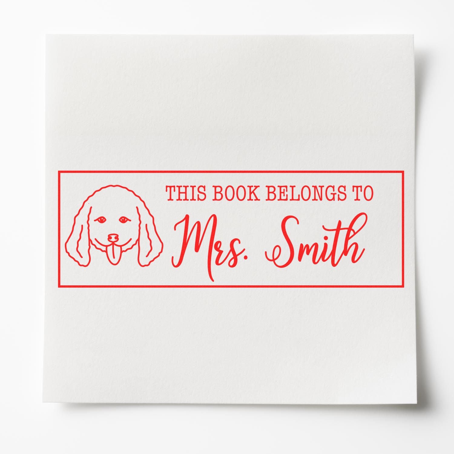 Personalized rubber book stamp with dog illustration, reading This Book Belongs to Mrs. Smith in red ink.