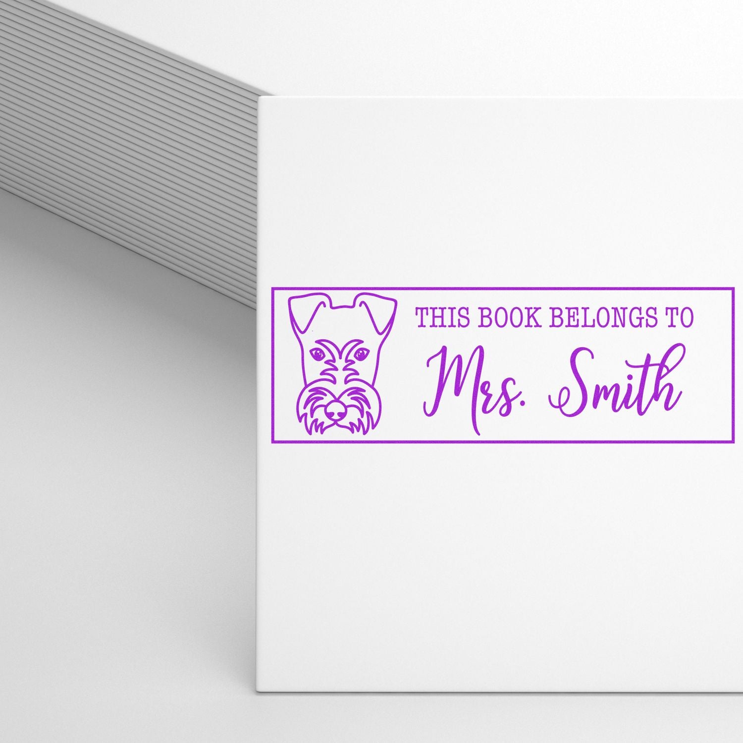 Personalized rubber book stamp with dog illustration and This Book Belongs to Mrs. Smith for custom library marking.