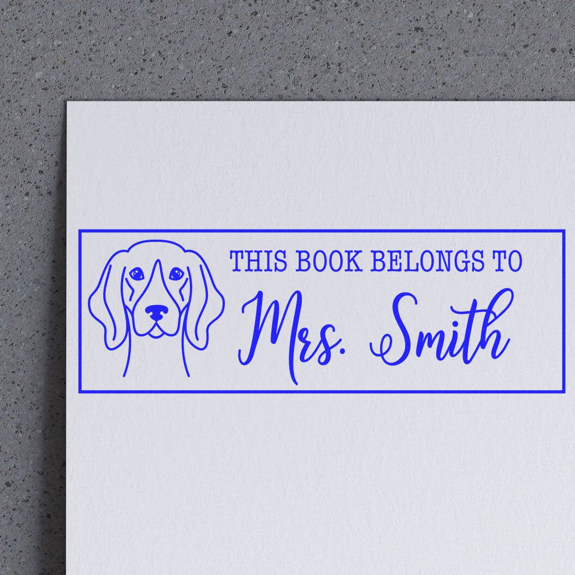 Personalized dog book rubber stamp reading This book belongs to Mrs. Smith for custom library marking.