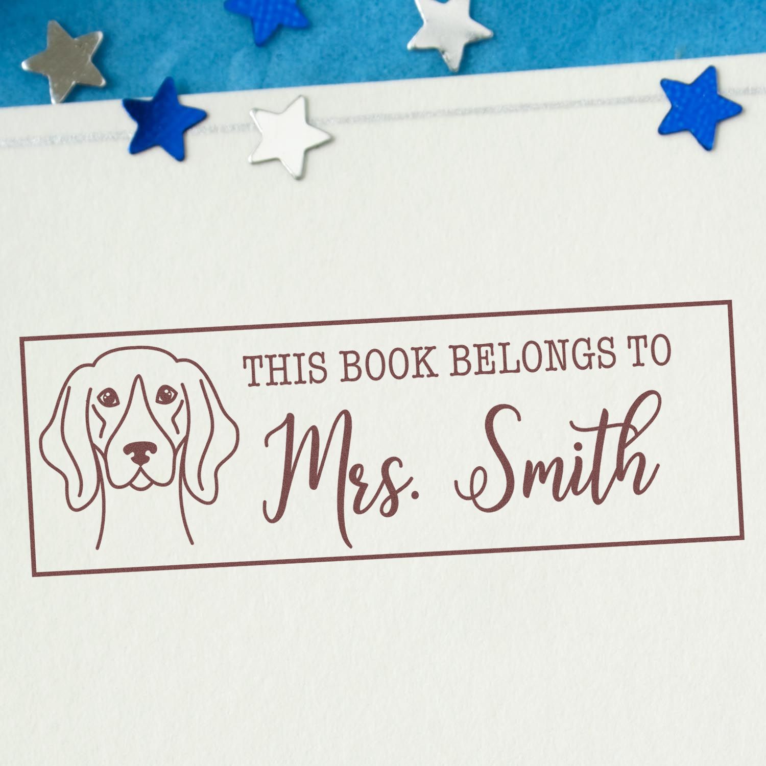 Personalized rubber book stamp with dog illustration and This Book Belongs to Mrs. Smith for library books.