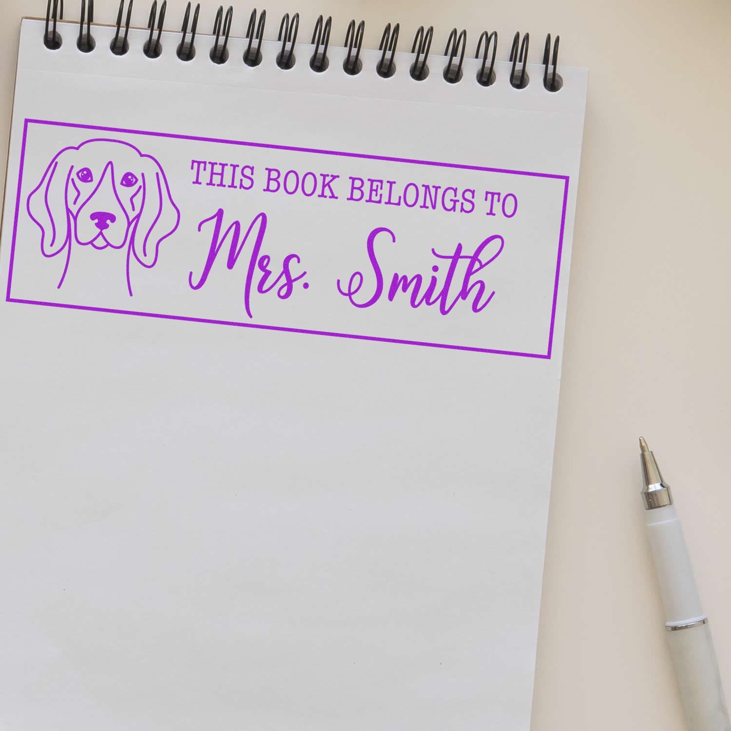 Custom rubber book stamp with dog design reading This Book Belongs to Mrs. Smith for personalized library books.