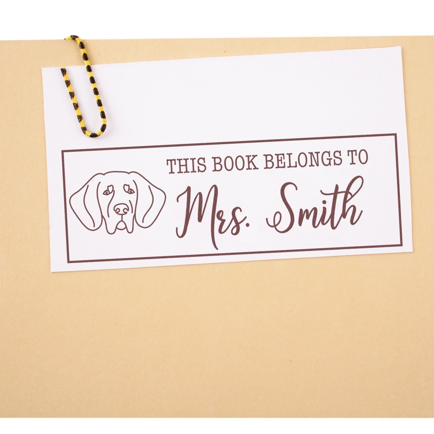 Personalized rubber book stamp with dog design and This Book Belongs to Ms. Smith for custom library books.