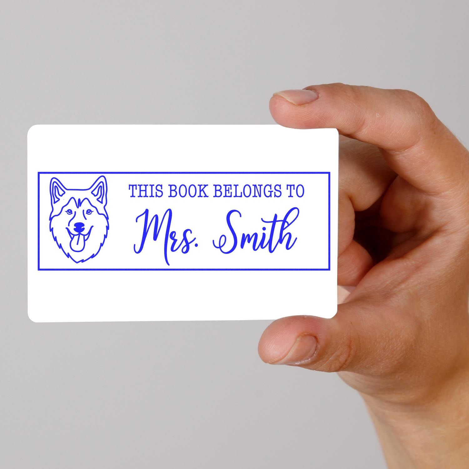Personalized rubber stamp bookplate with dog icon, reading This Book Belongs to Mrs. Smith for custom books.