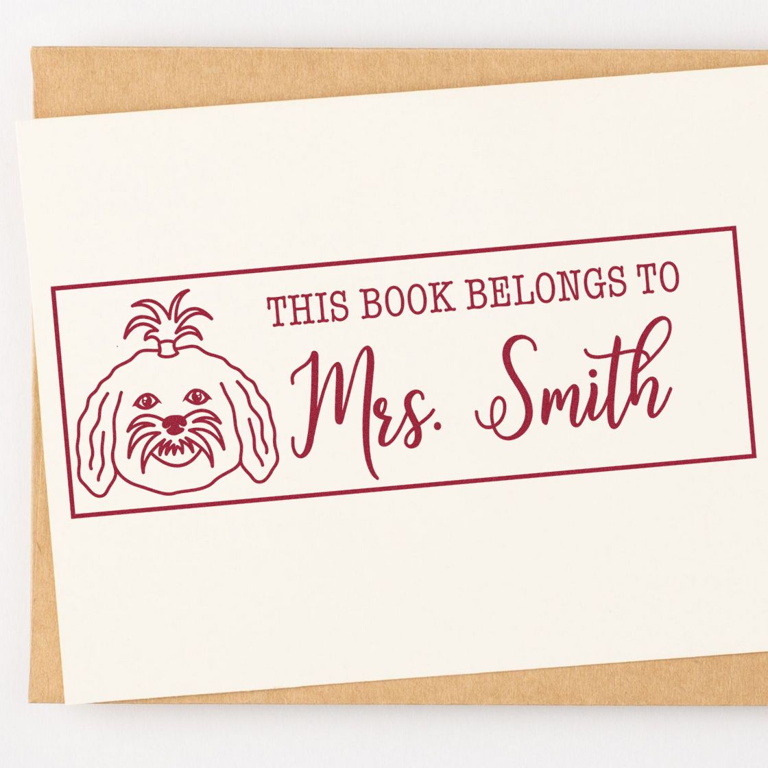 Personalized book stamp reading This Book Belongs to Mrs. Smith with dog illustration for custom rubber stamping.