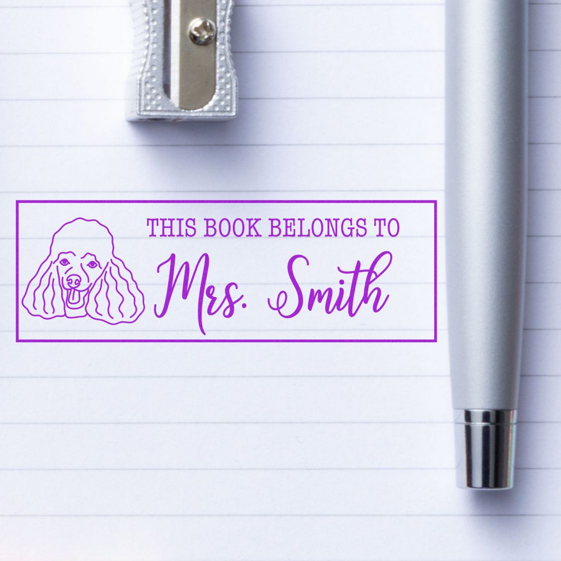 Personalized rubber book stamp reading This Book Belongs to Mrs. Smith with poodle icon for custom library labeling.