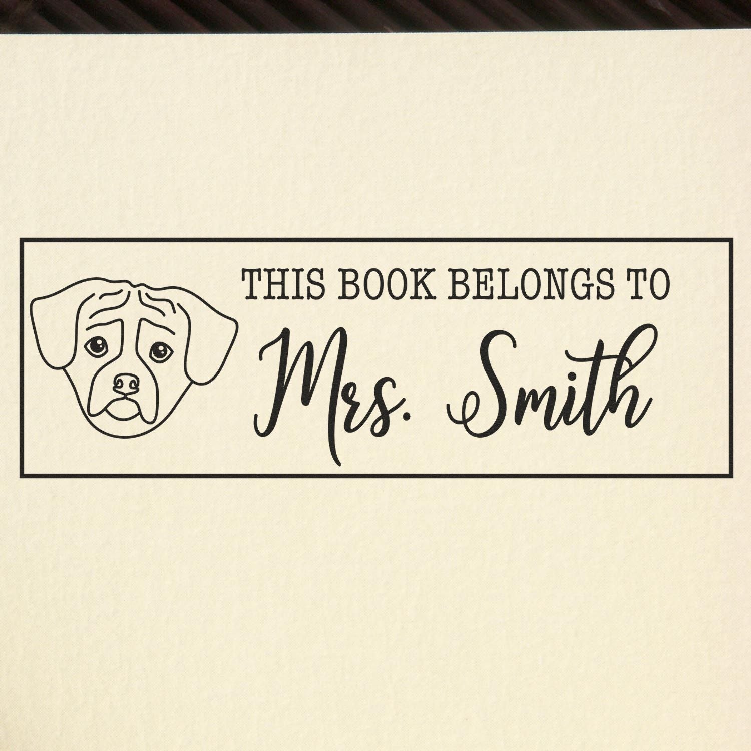 Custom rubber book stamp with dog illustration and This Book Belongs to Mrs. Smith personalized owner mark.