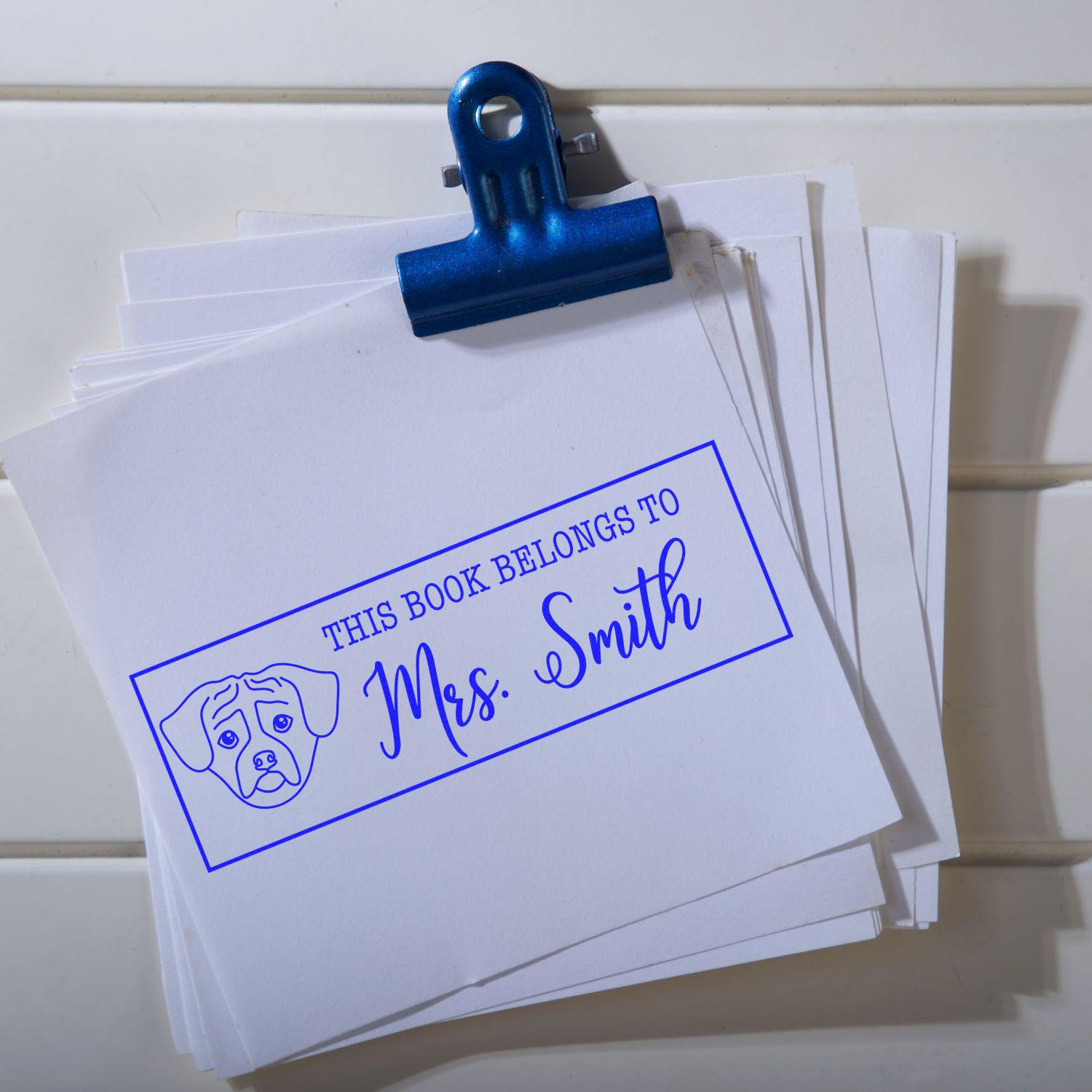 Custom rubber book stamp reading This Book Belongs to Mrs. Smith with dog icon for personalized library labeling.