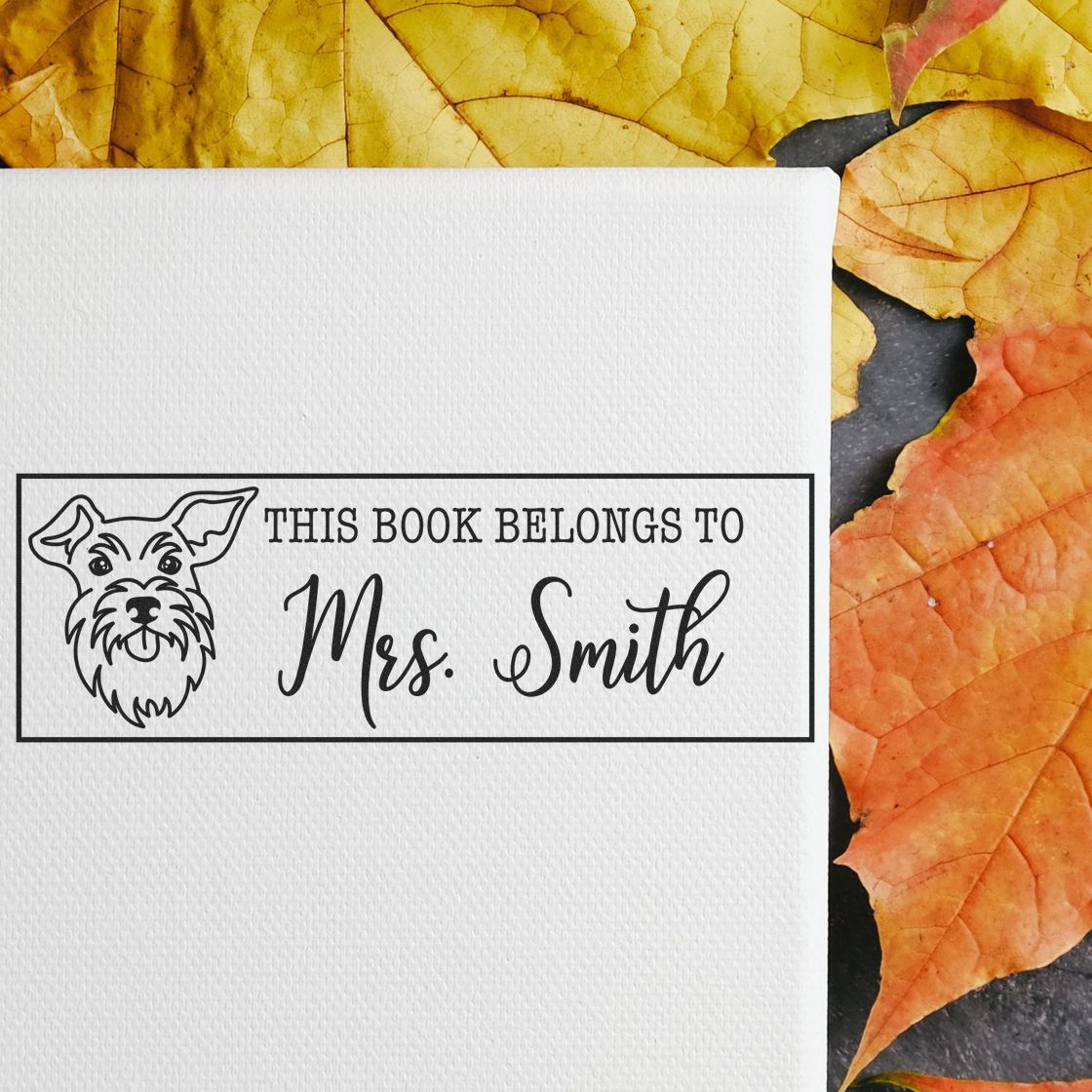 Custom rubber stamp impression with dog icon and This Book Belongs to Mrs. Smith for personalized book labels.