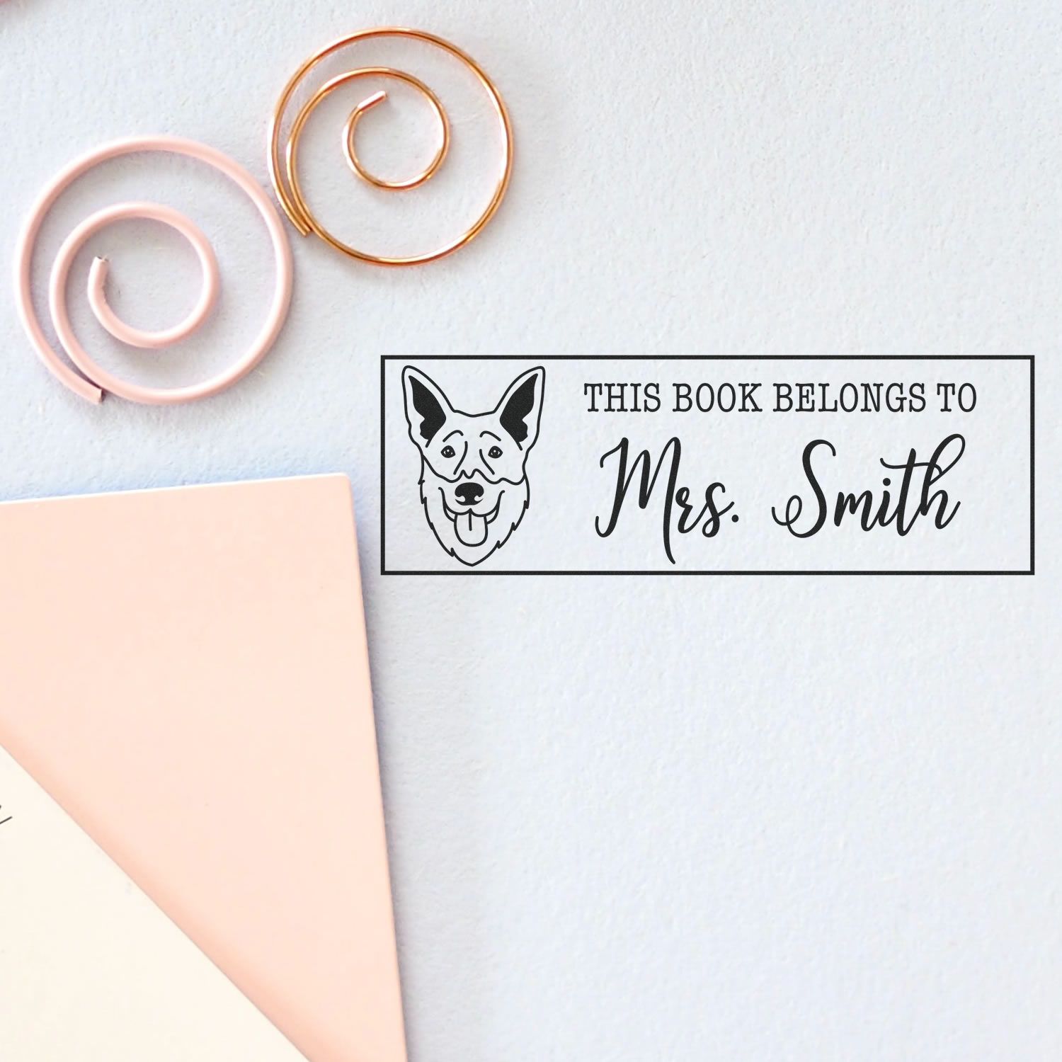 Custom rubber book stamp with dog illustration and This book belongs to Mrs. Smith text for personal library labeling.