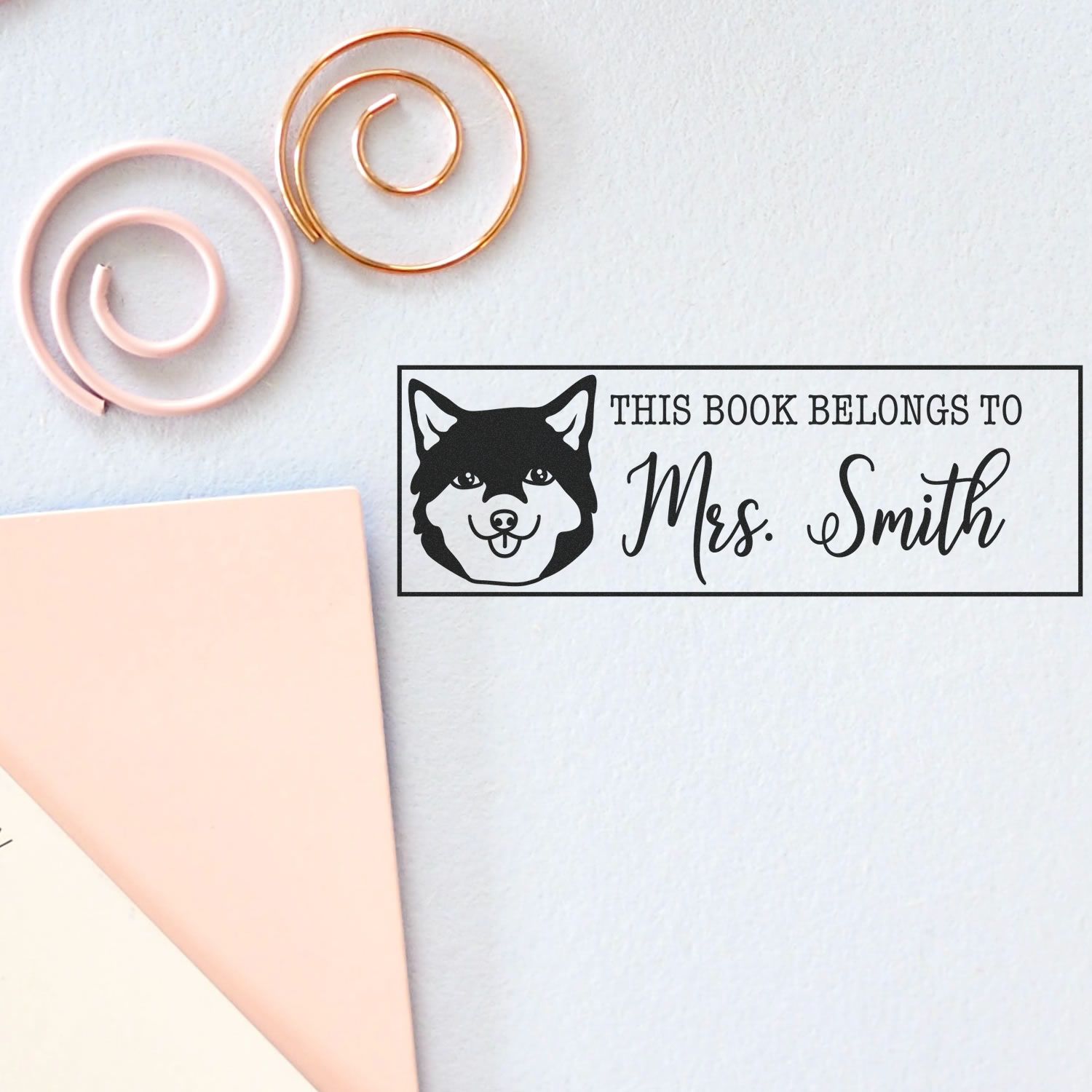 Personalized book rubber stamp design with dog illustration and This Book Belongs to Mrs. Smith bookplate text.