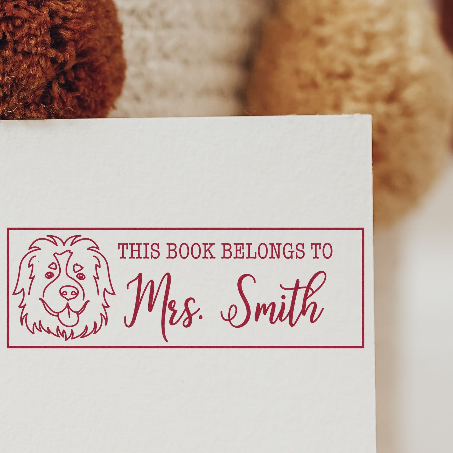 Custom bookplate rubber stamp with dog illustration and This Book Belongs to Mrs. Smith on white paper.