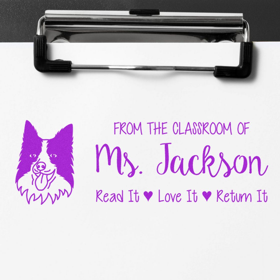 Custom teacher rubber stamp on clipboard with dog logo and From the classroom of Ms. Jackson, Read it, Love it, Return it text.