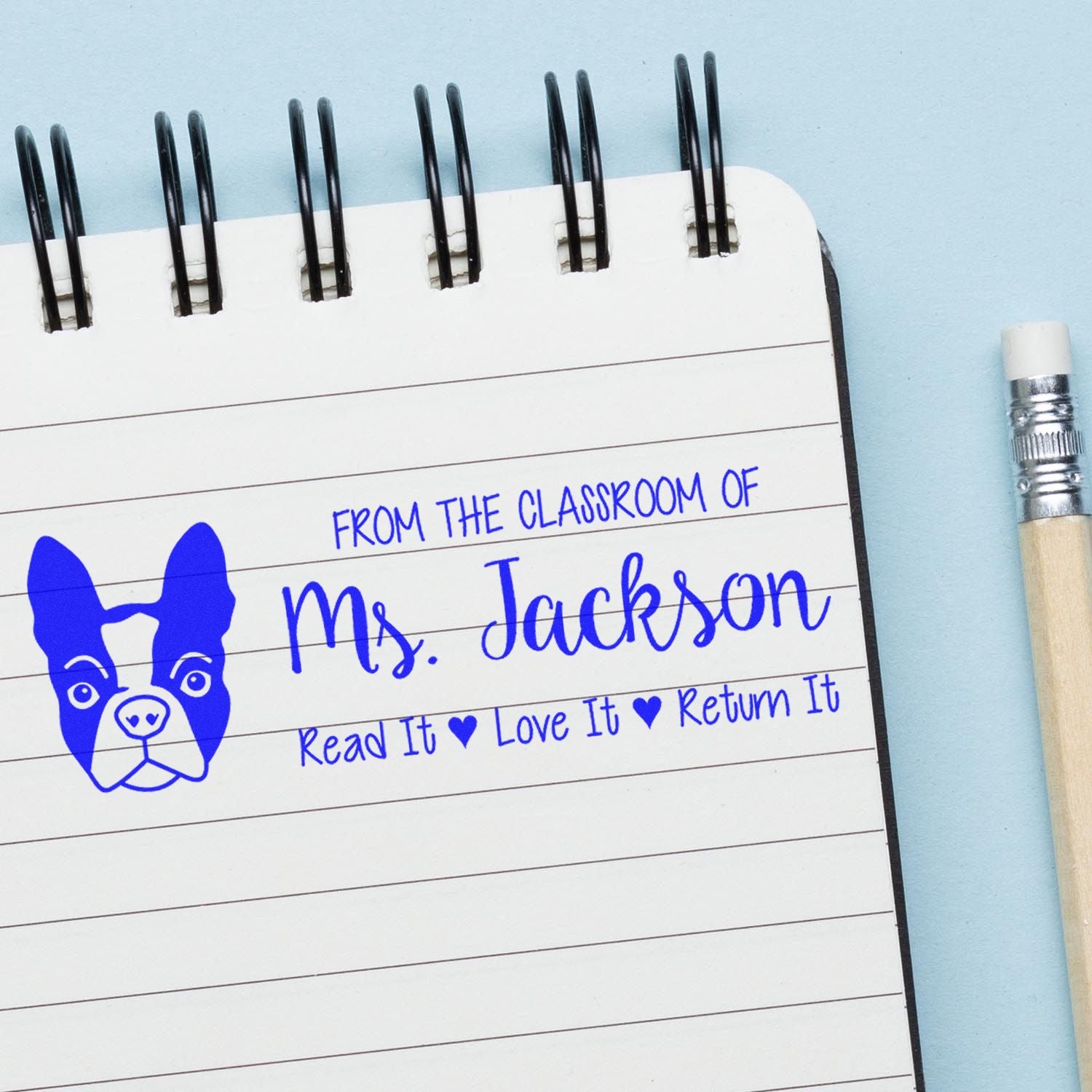 Custom teacher rubber stamp on notebook page reading From the classroom of Ms. Jackson with Read It Love It Return It dog design.