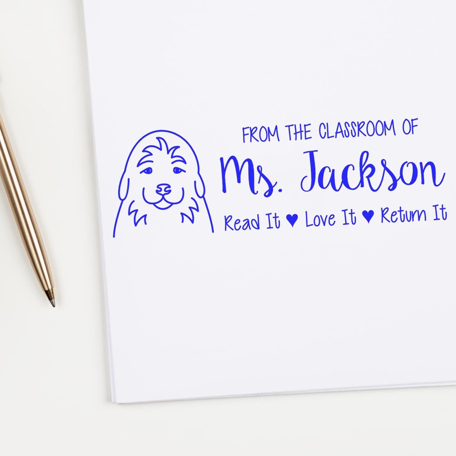 Blue custom teacher rubber stamp reading From the classroom of Ms. Jackson, Read It Love It Return It with dog icon.