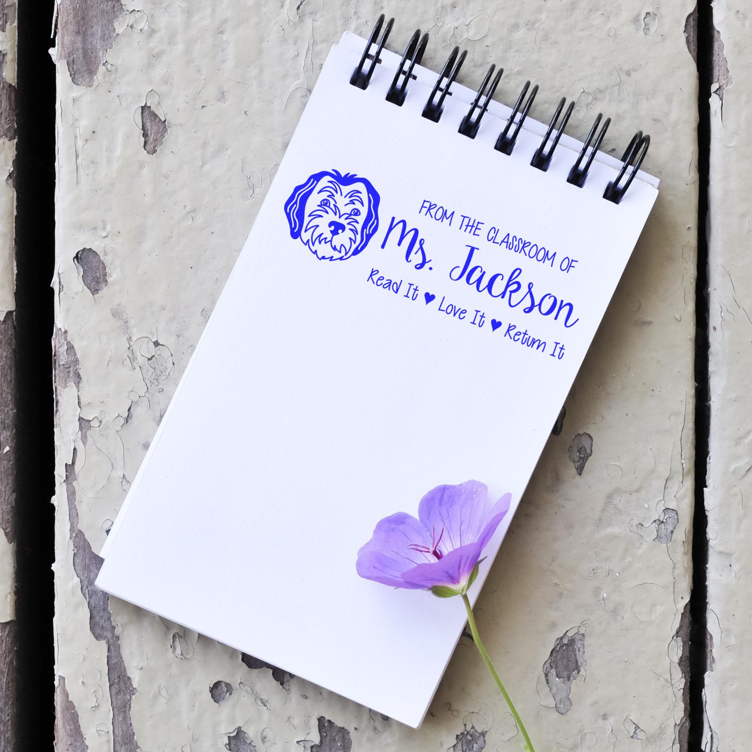 Personalized teacher rubber stamp with dog logo on spiral notebook, reading From the classroom of Ms. Jackson, Read it Love it Return It.