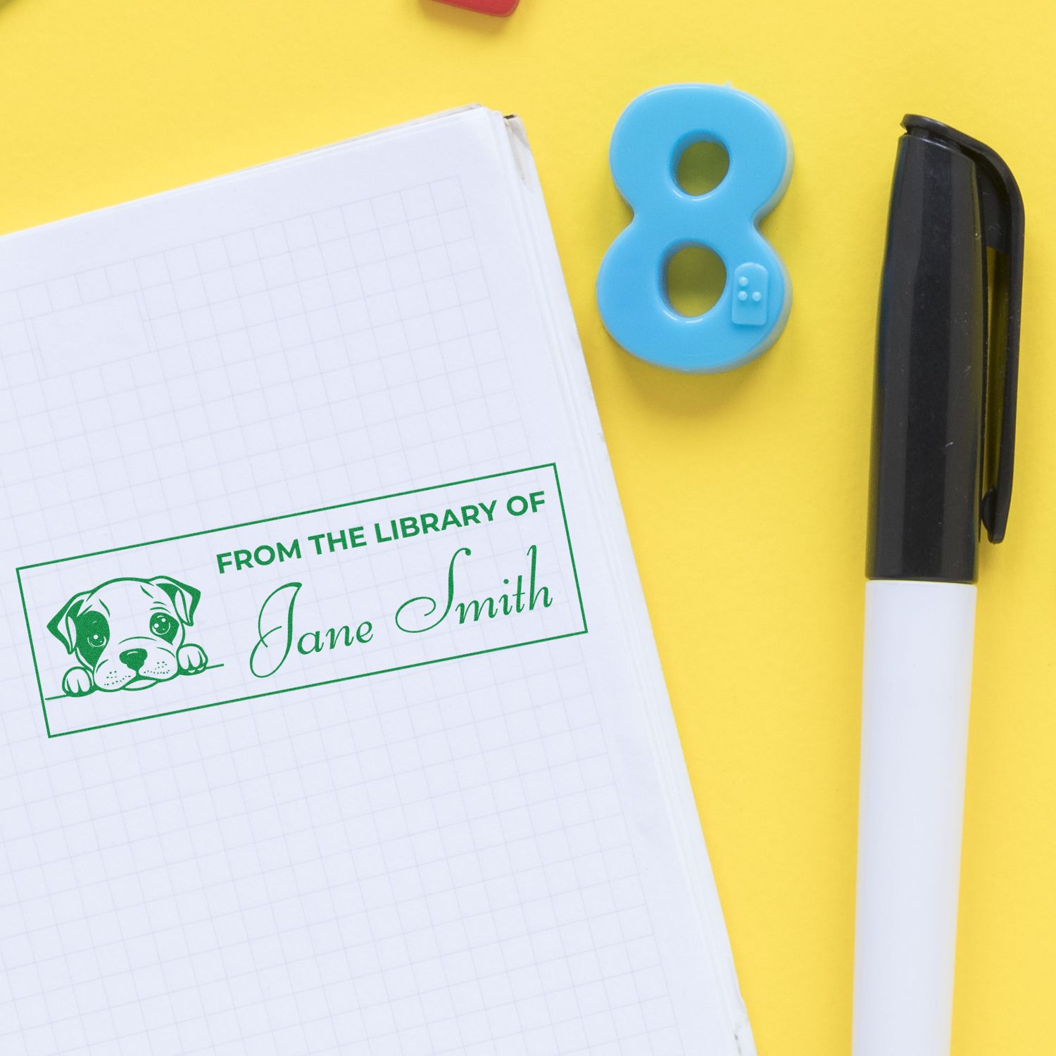 Custom library rubber stamp with dog design stamped on notebook, featuring From the Library of Jane Smith text.