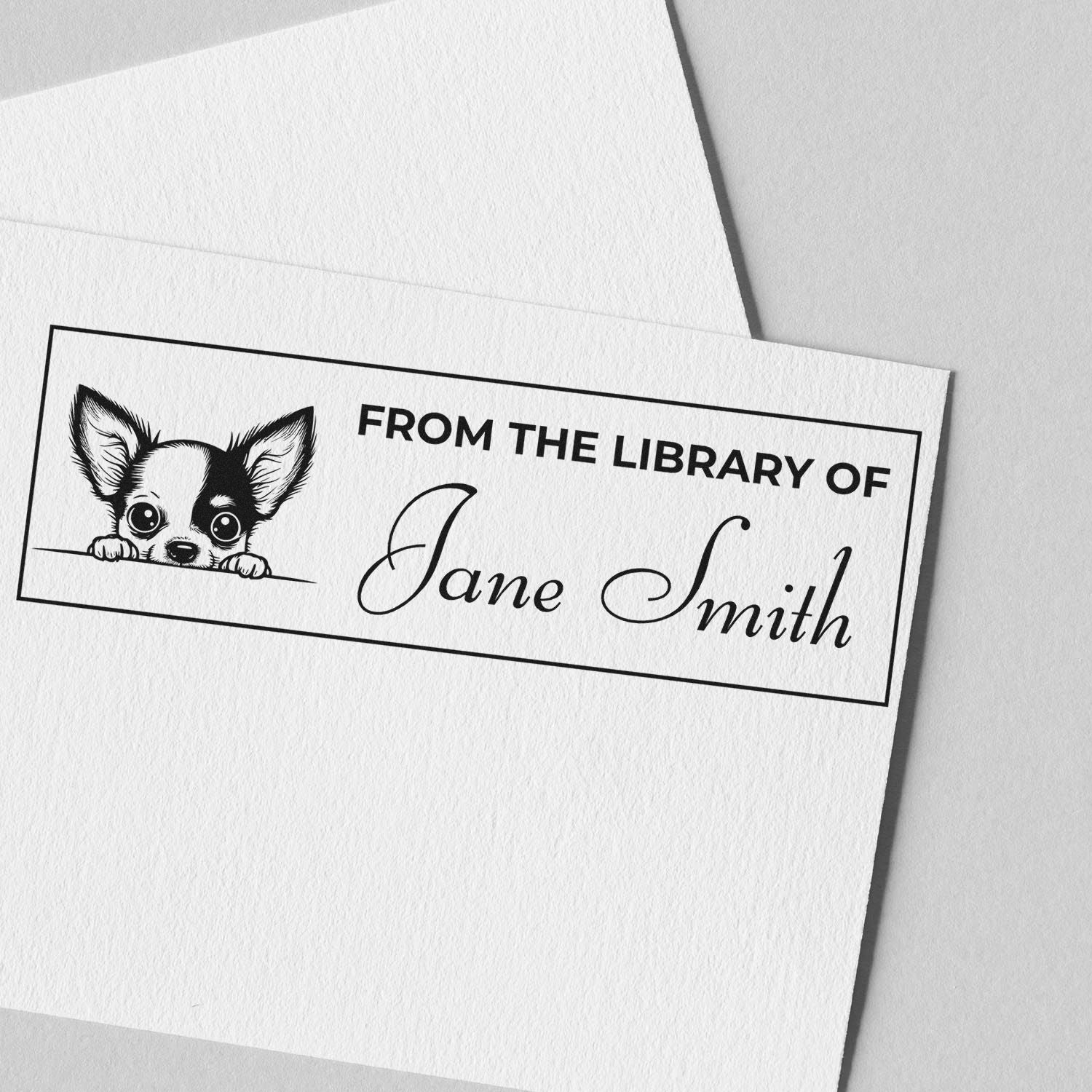 Custom library rubber stamp with puppy design and personalized From the Library of Jane Smith text on white paper.