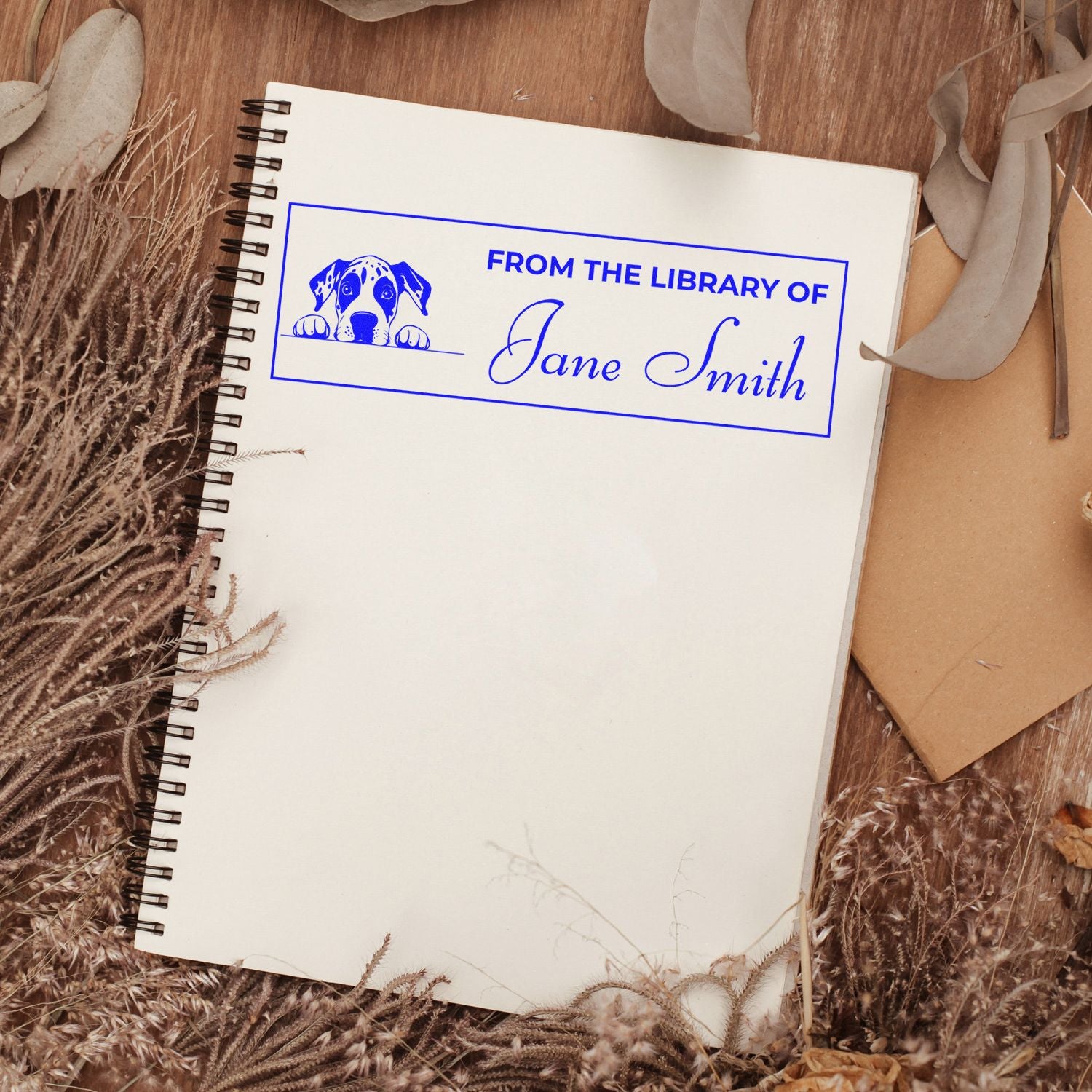 Personalized dog library rubber stamp imprint reading From the Library of Jane Smith on a notebook.