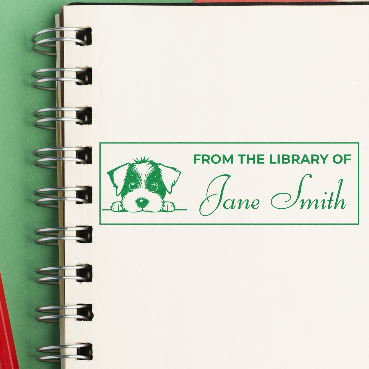 Personalized rubber book stamp with dog illustration reading From the Library of Jane Smith on a notebook page.
