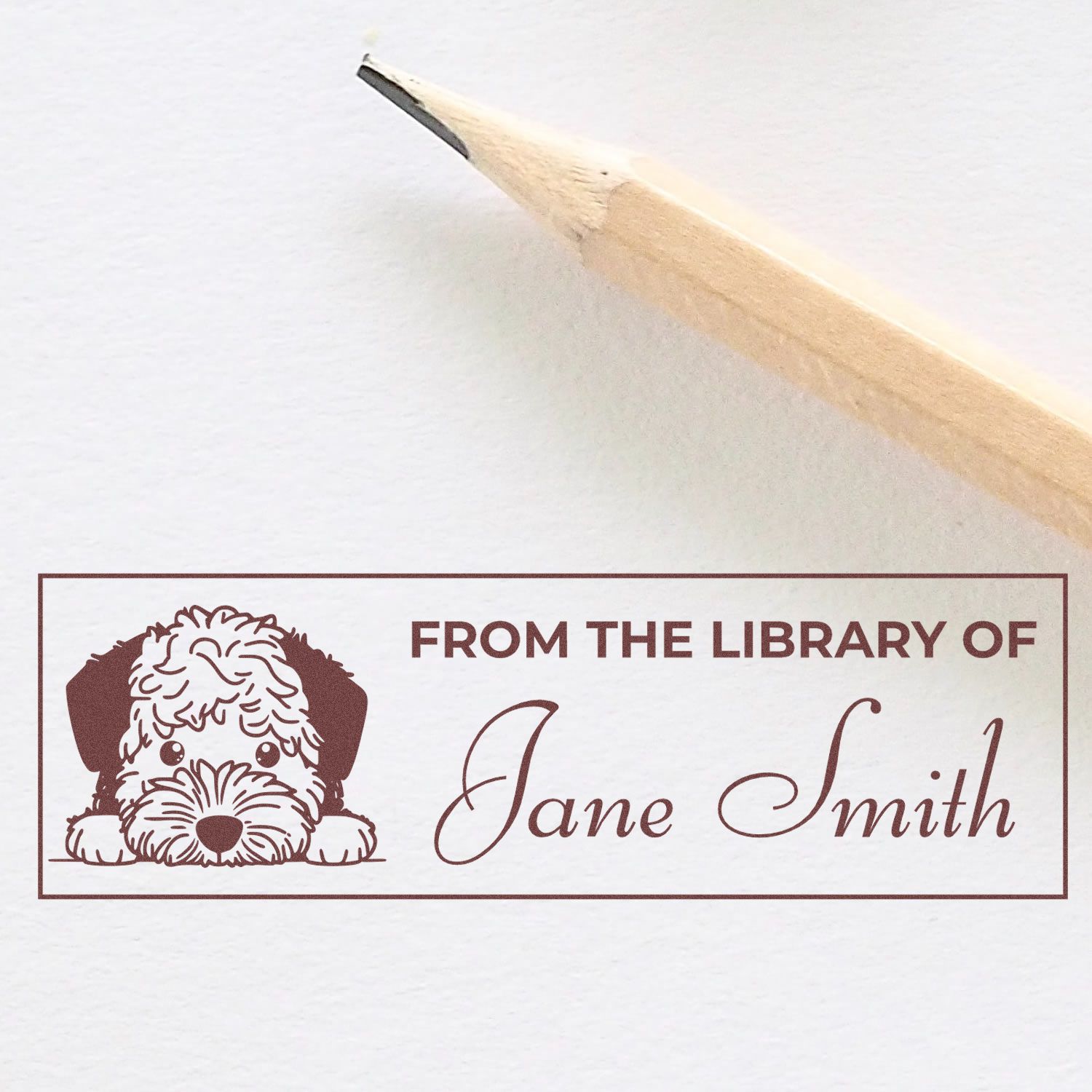 Personalized library book rubber stamp with dog illustration and From the Library of Jane Smith text, shown with pencil.