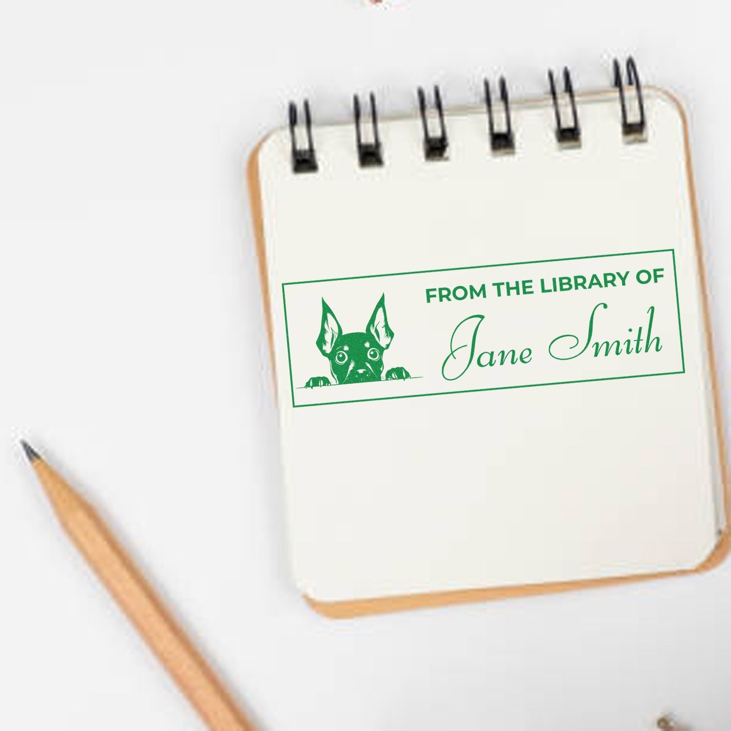 Personalized library bookplate rubber stamp with dog design reading From the Library of Jane Smith on a notebook