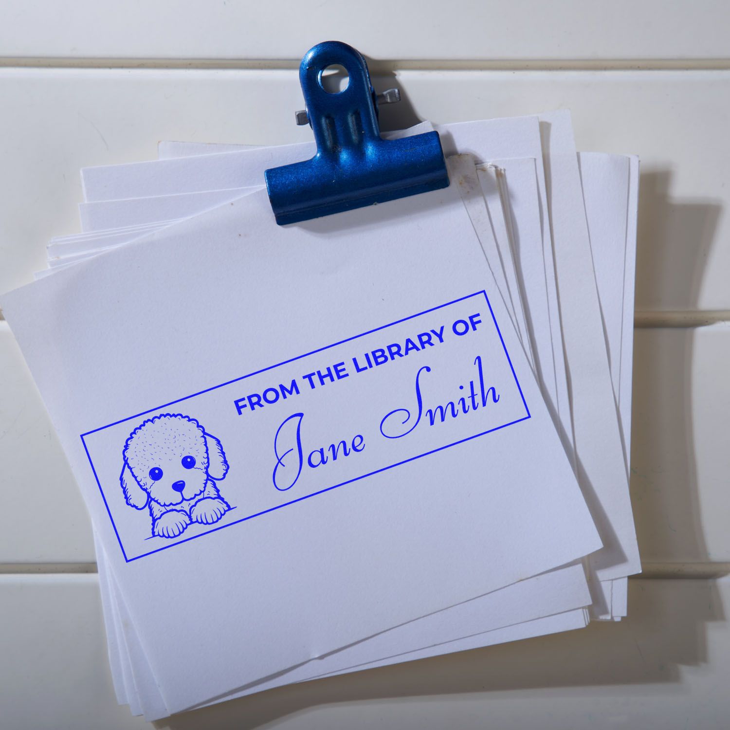 Custom rubber stamp bookplate reading From the Library of Jane Smith with puppy design on stacked papers