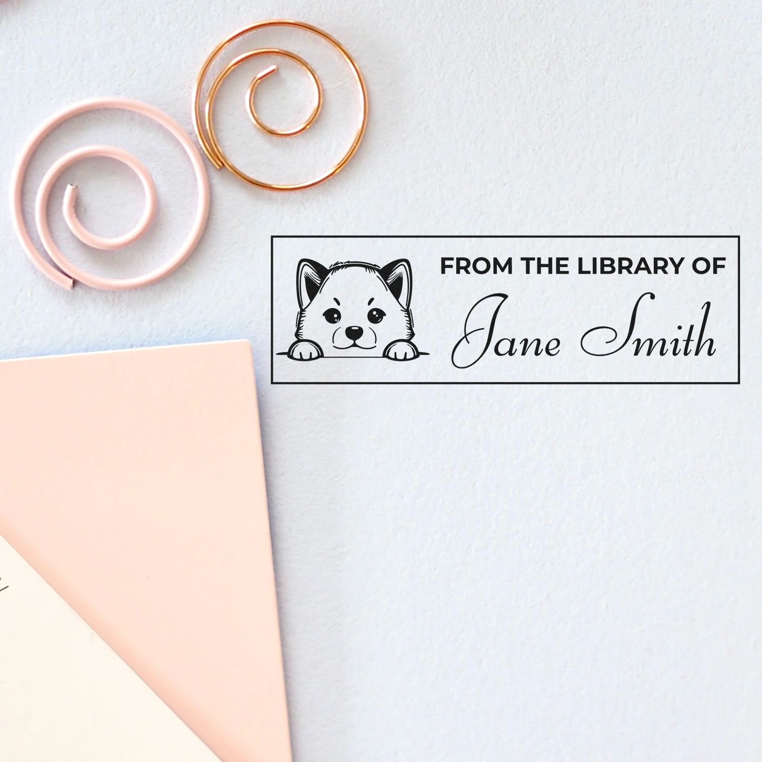 Personalized rubber stamp reading From the Library of Jane Smith with dog illustration for bookplates and stationery.