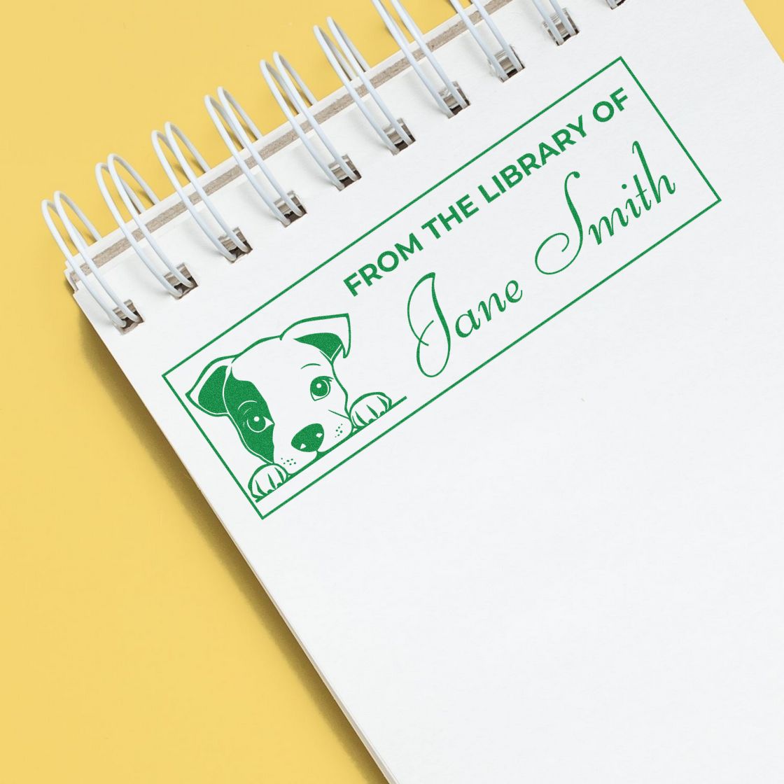Custom library rubber stamp with dog design and personalized name Jane Smith on a notebook page for book labeling.