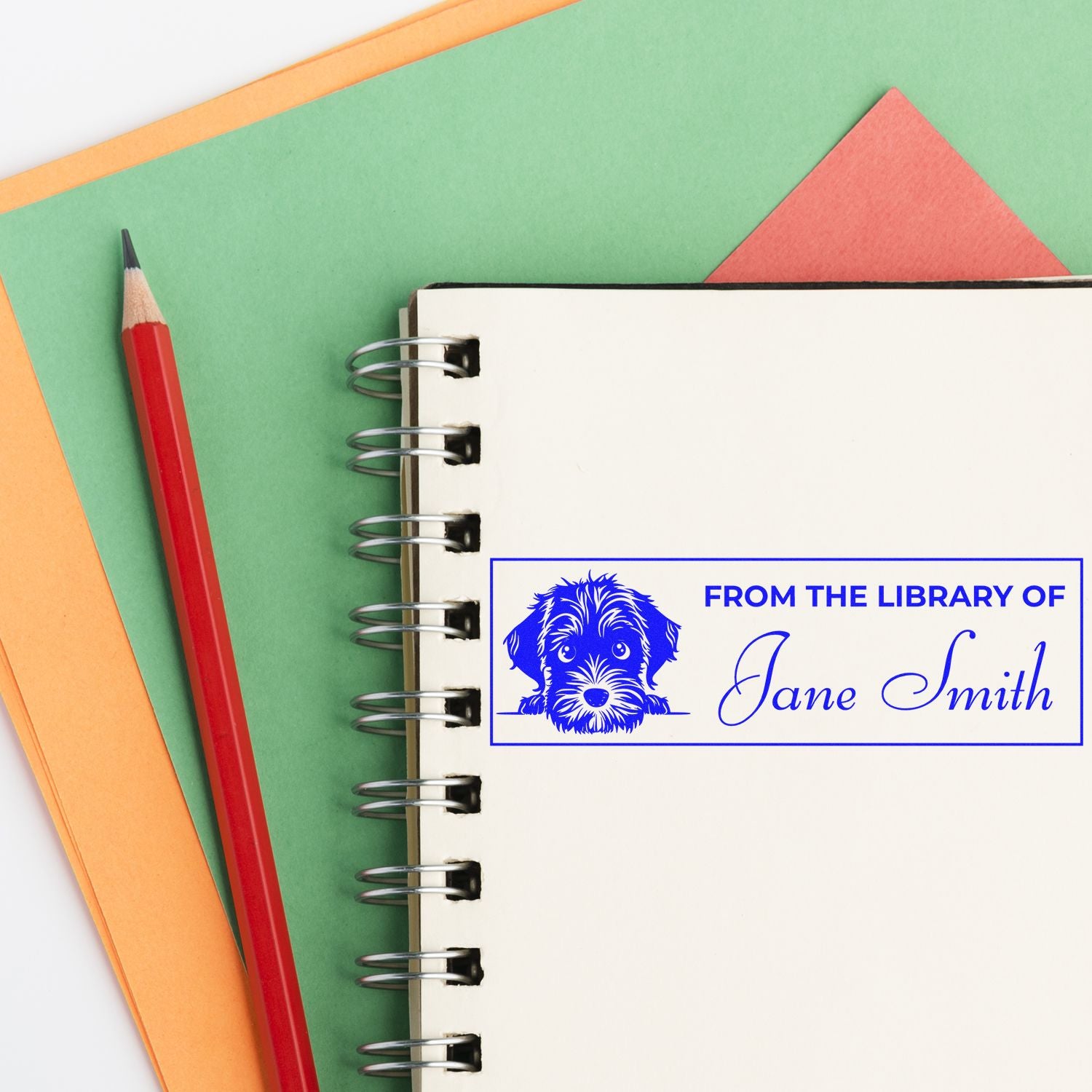 Personalized rubber stamp reading From the Library of Jane Smith with dog design on a notebook, ideal for custom book marking.