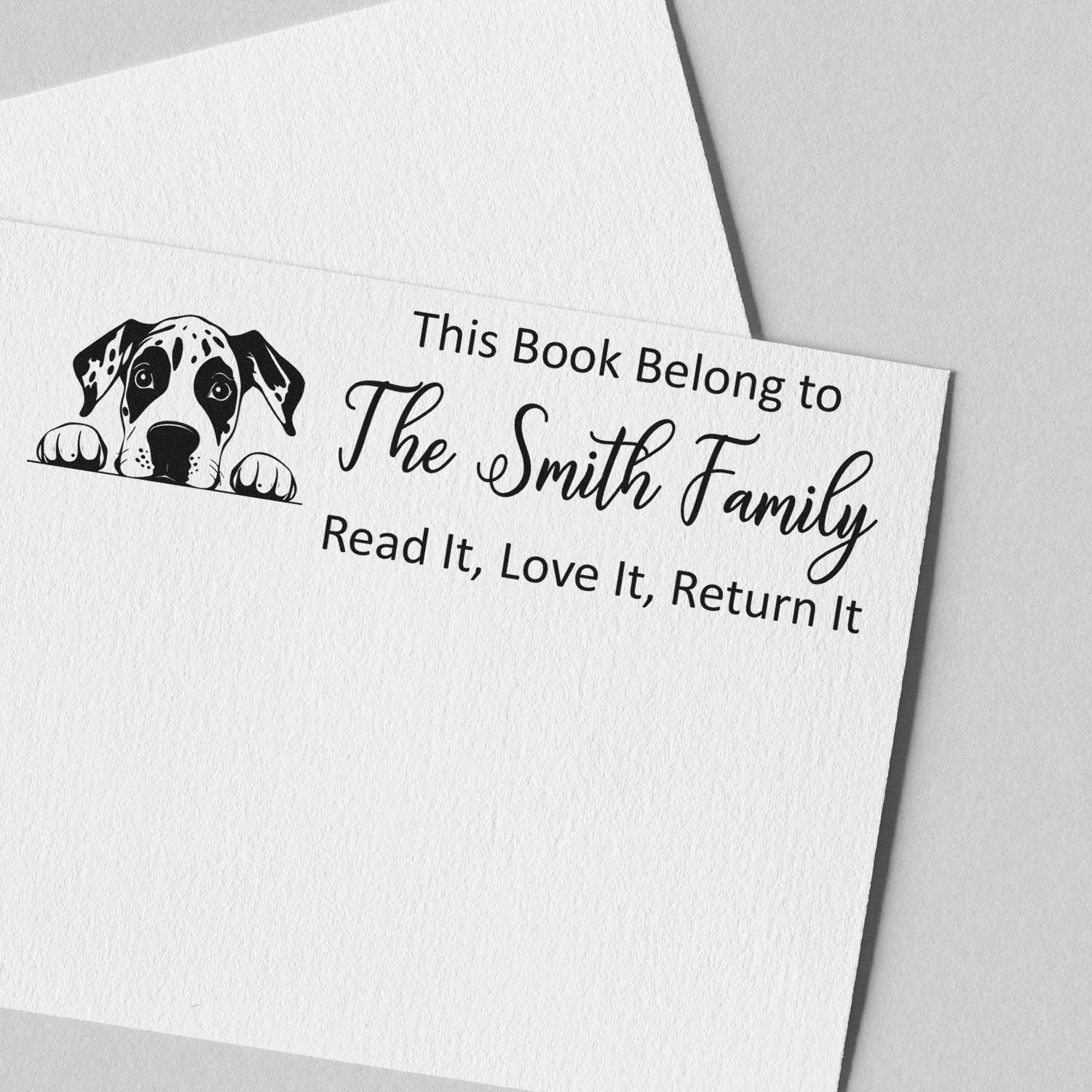 Custom book rubber stamp with dog illustration and personalized This Book Belong to The Smith Family return-it message.