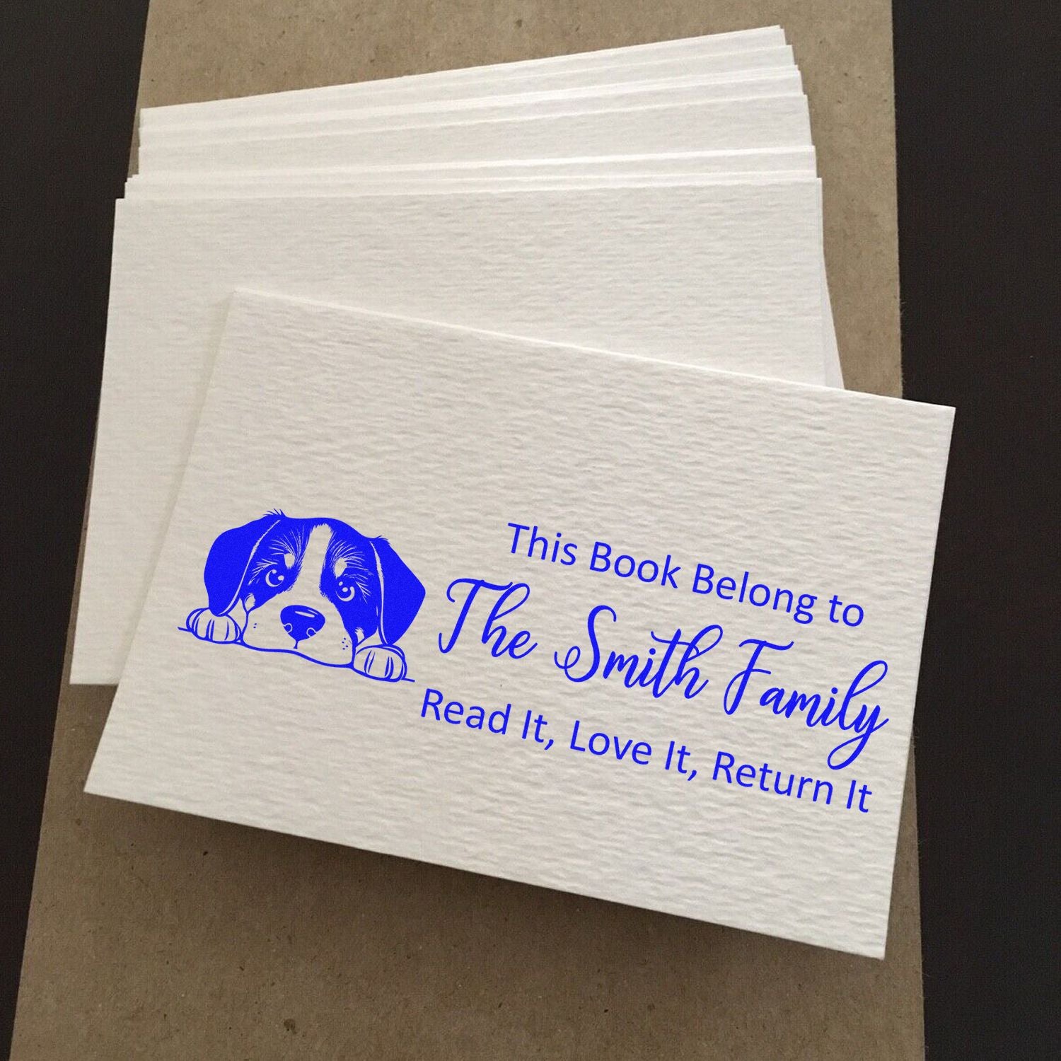 Personalized rubber book stamp with puppy design, reading This Book Belongs to The Smith Family for marking family books.