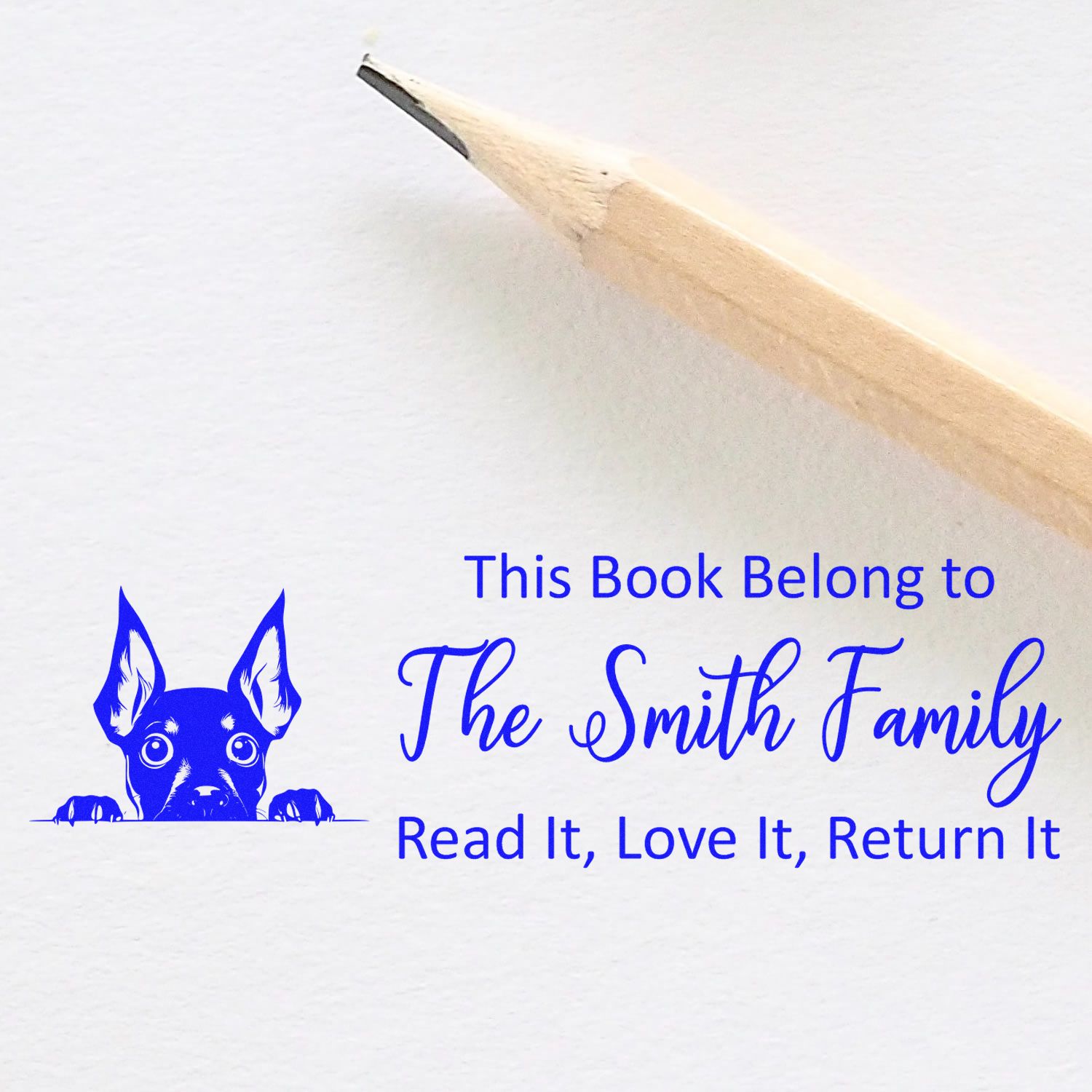 Personalized book rubber stamp with dog graphic and "This Book Belongs to The Smith Family, Read It, Love It, Return It."