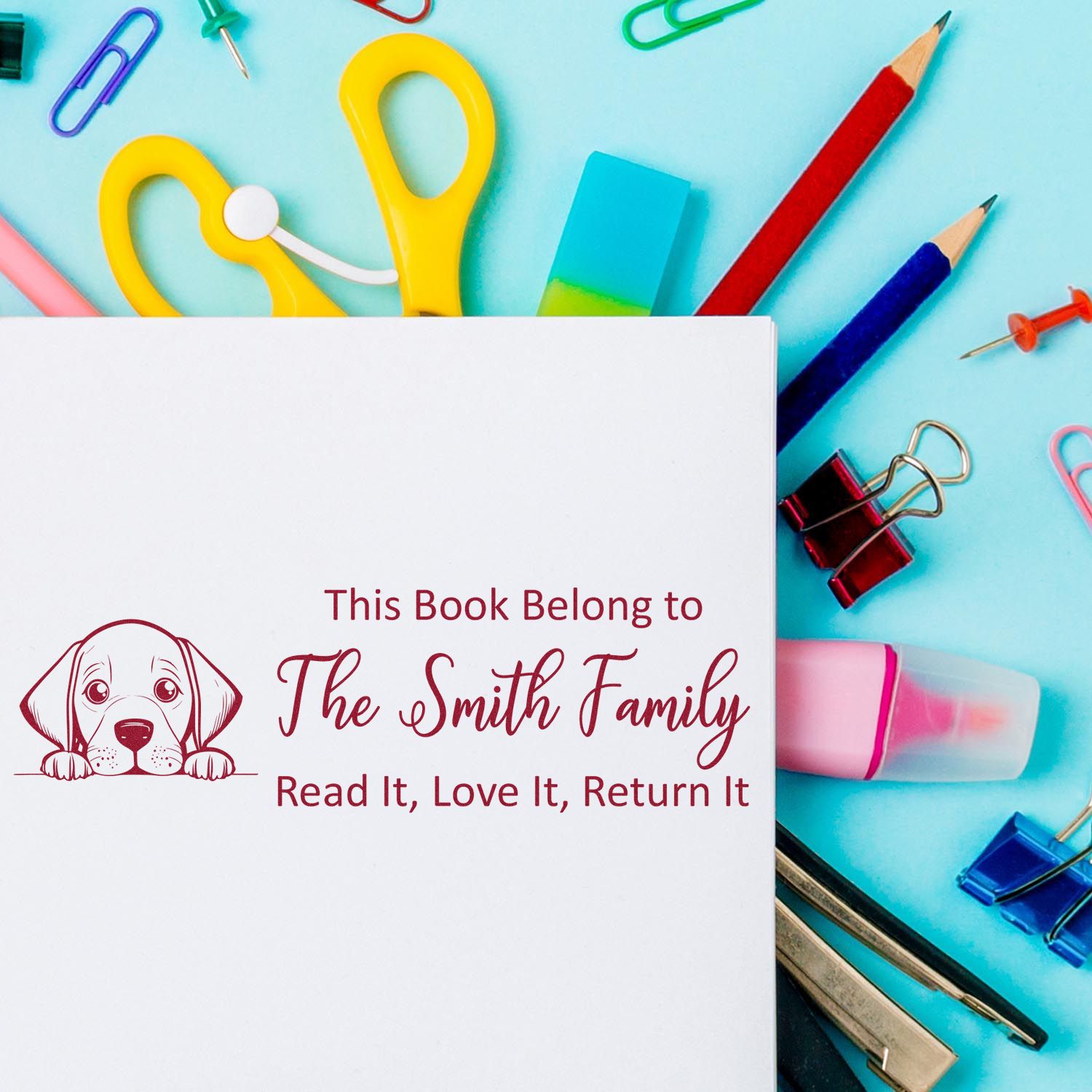 Personalized rubber book stamp with dog design, reading This Book Belongs to The Smith Family for marking home library books.