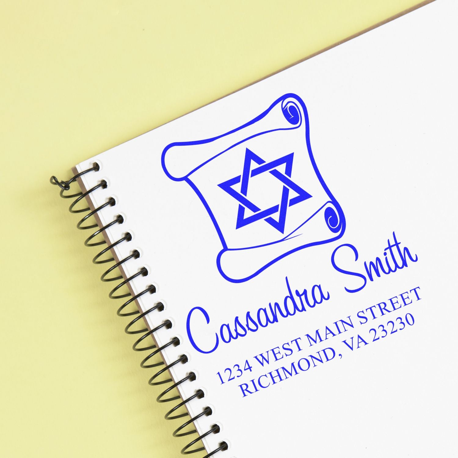 Custom rubber stamp design with name, logo, and Richmond, VA address on a spiral notebook cover.