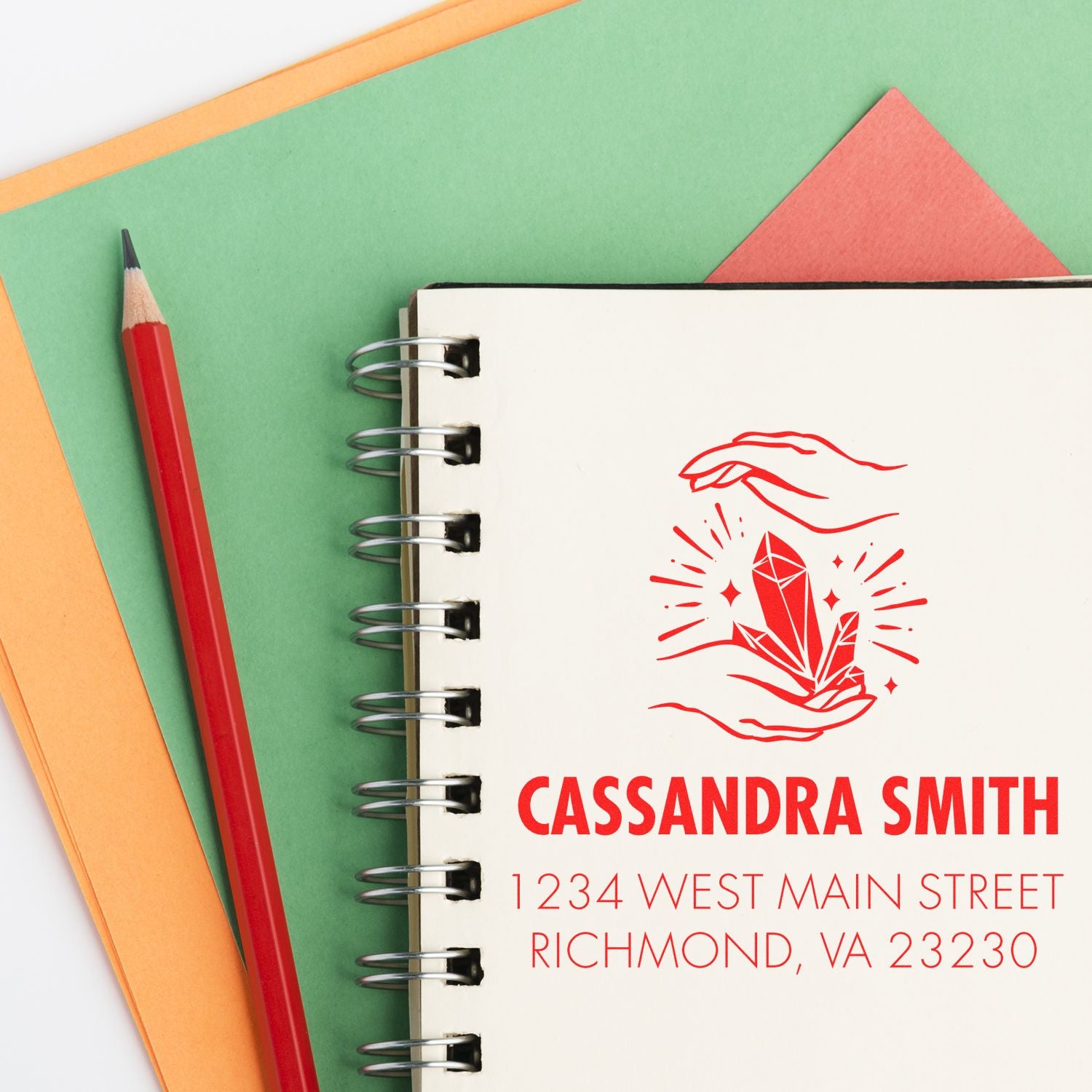 Personalized rubber stamp with crystal hands logo, Cassandra Smith name, and Richmond, VA address on a notebook.