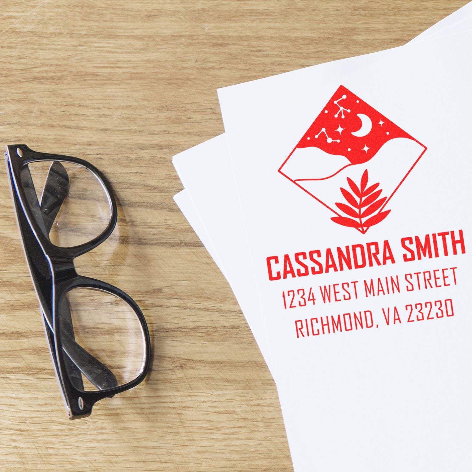 Custom rubber address stamp on stationery with name, street address, and logo design for mailing and branding.