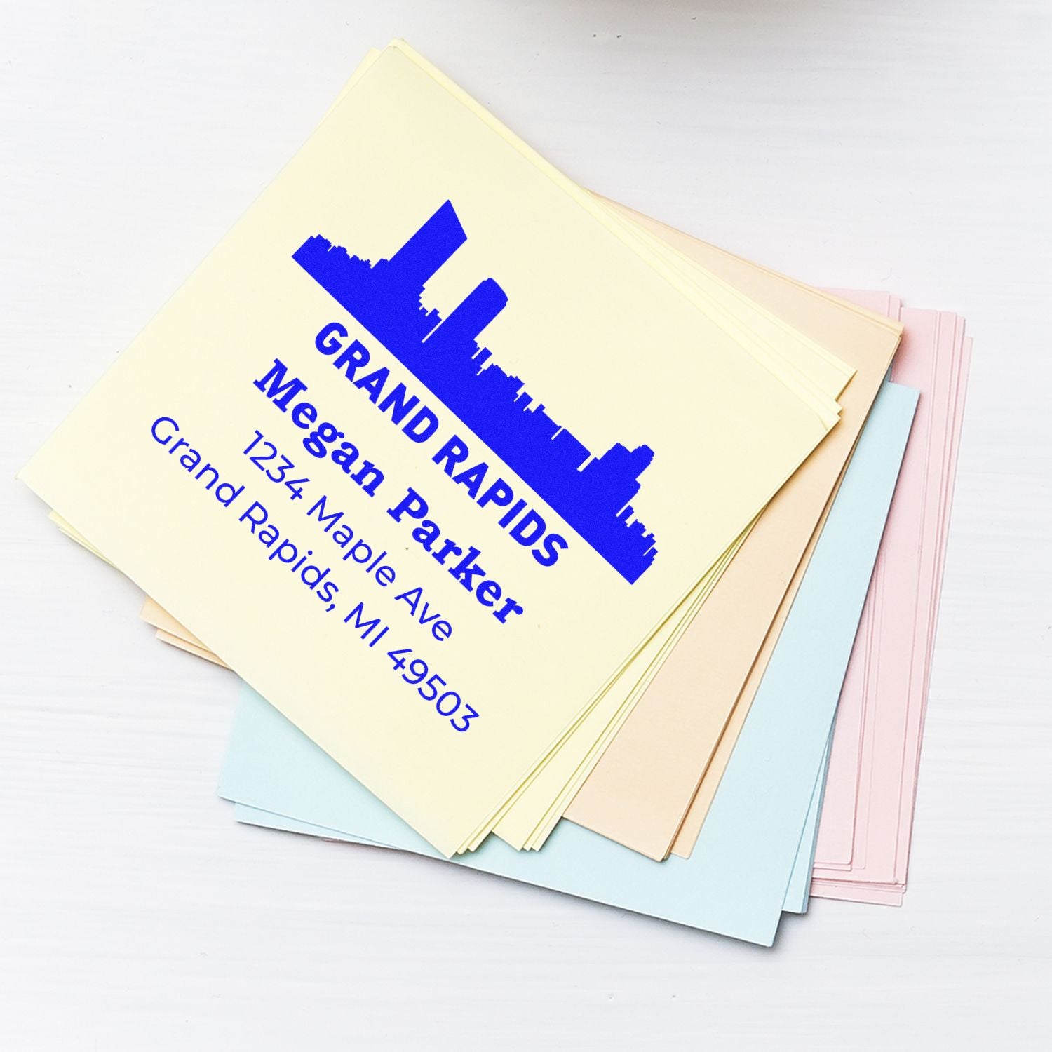 Custom address rubber stamp sample for Grand Rapids business on pastel cardstock.