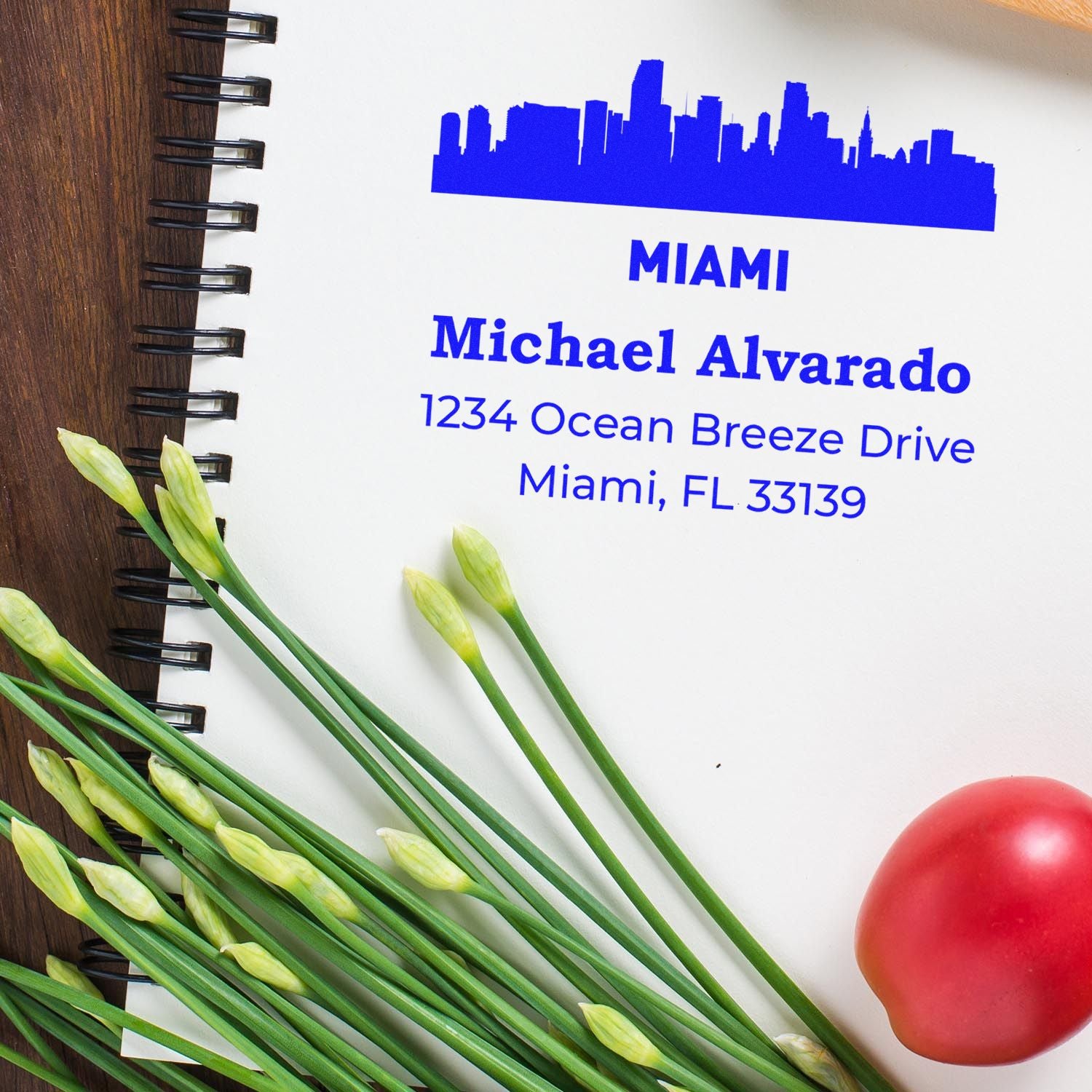 Custom Miami return address rubber stamp with skyline design, personalized name, and blue ink on notebook.