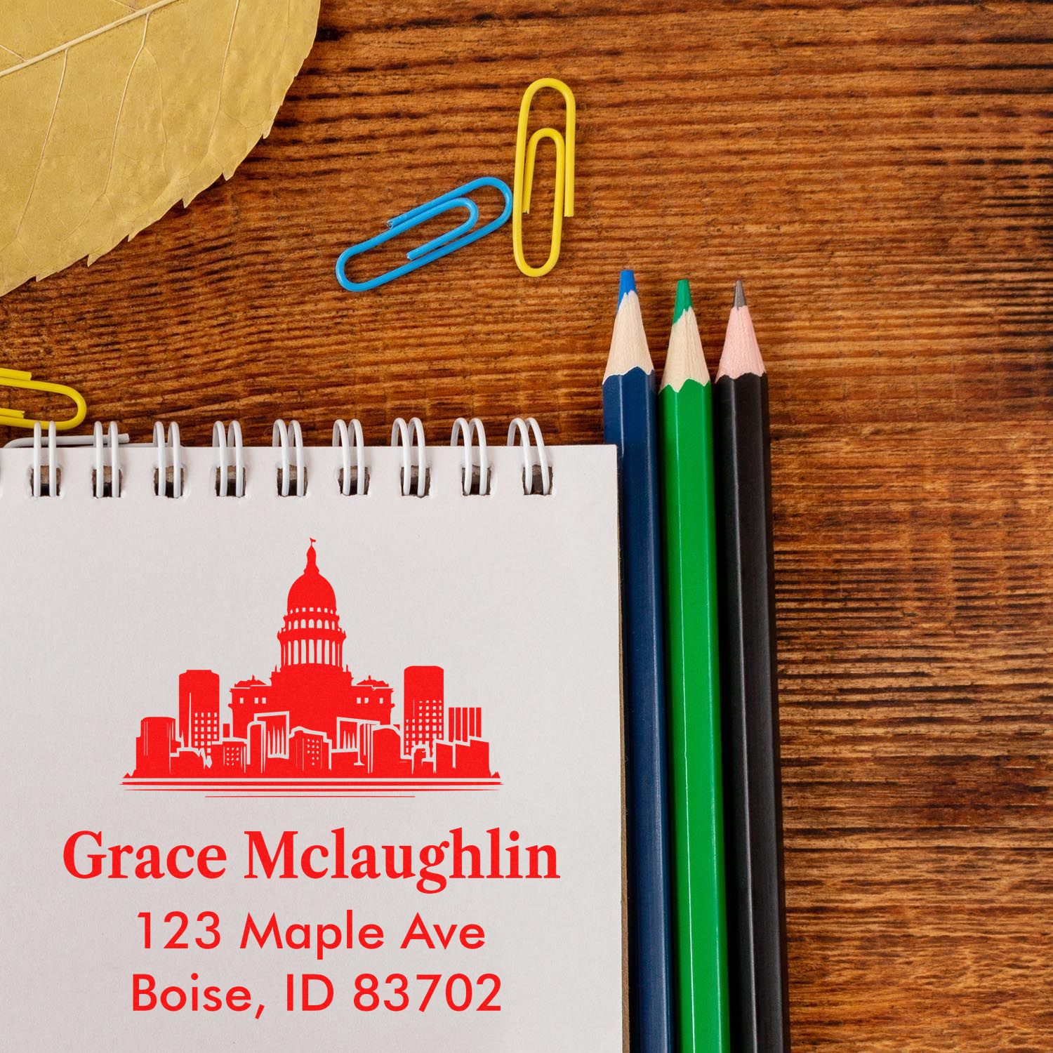 Personalized address rubber stamp with skyline design on notebook, showing Grace McLaughlin, Boise, ID mailing details.