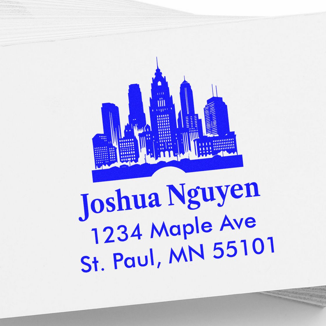 Custom blue city skyline address rubber stamp for Joshua Nguyen, 1234 Maple Ave, St. Paul, MN 55101.