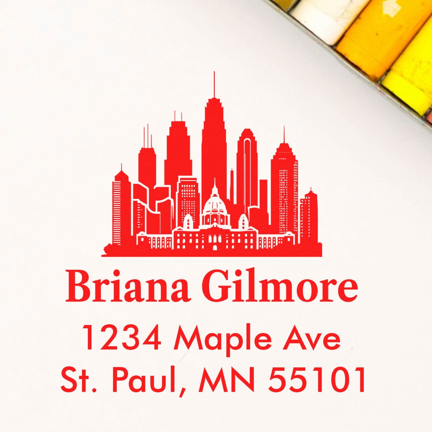 Custom return address rubber stamp with skyline design, featuring Briana Gilmore, 1234 Maple Ave, St. Paul, MN 55101.