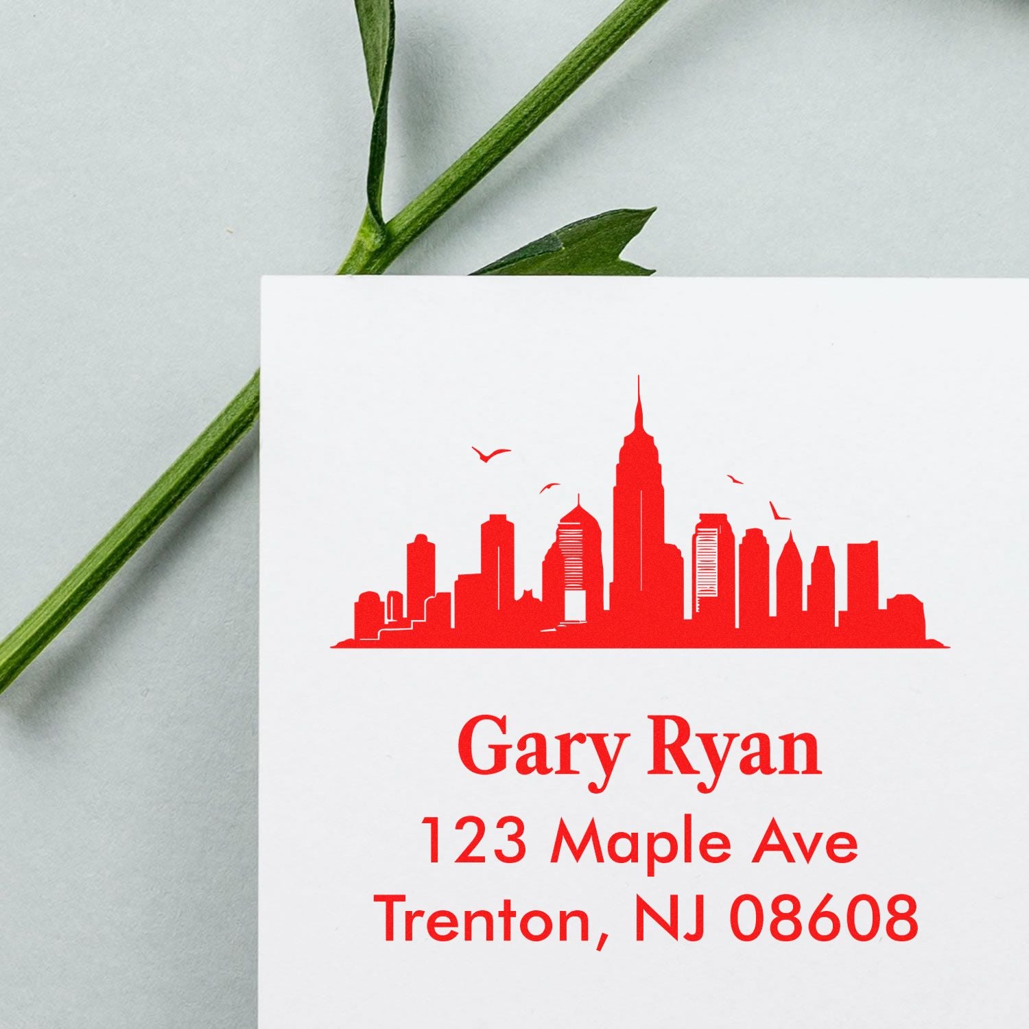 Custom return address rubber stamp with red skyline design, Gary Ryan, 123 Maple Ave, Trenton, NJ 08608.