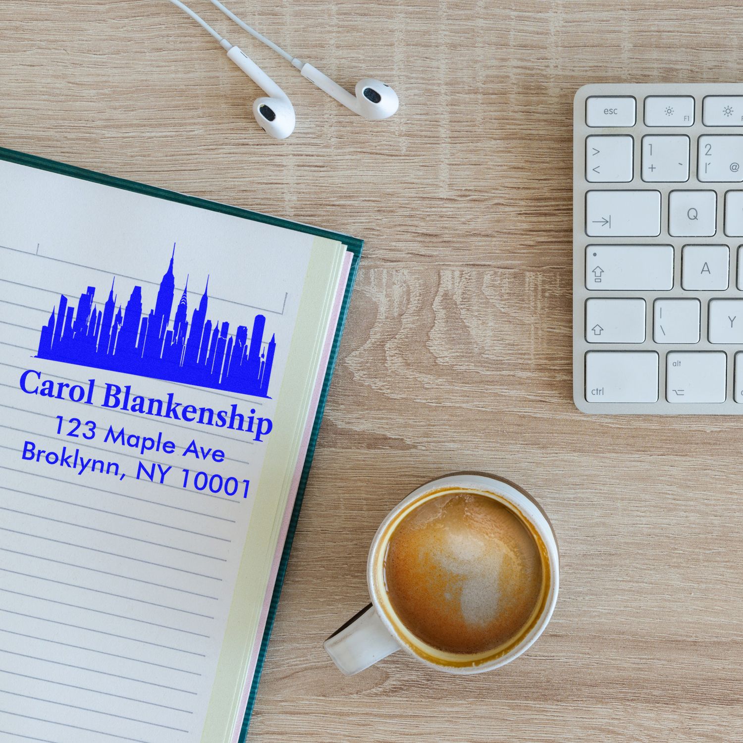 Custom return address rubber stamp on notebook beside keyboard and coffee for branded business stationery.